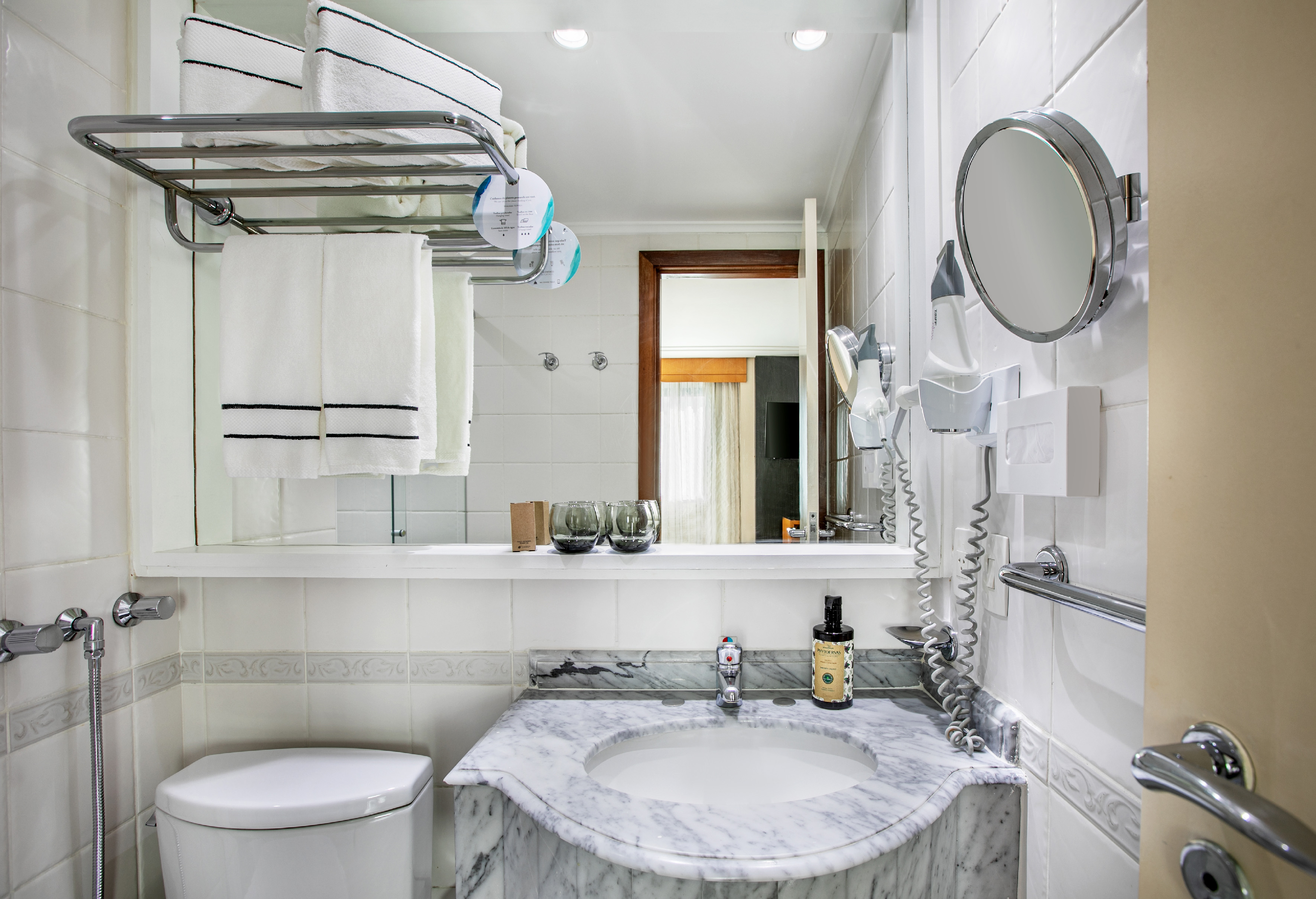 Clean hotel bathroom with marble vanity, sink, mirror, toilet, and white towels.