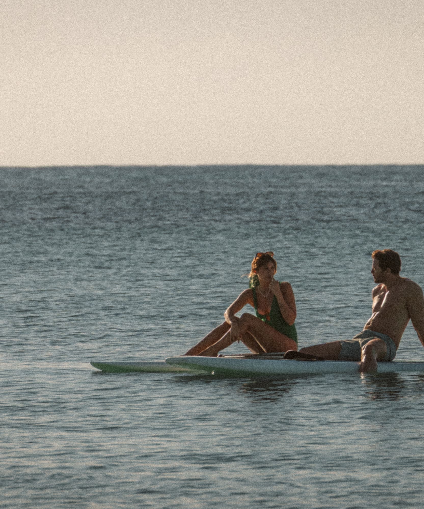 a man and woman sitting on surfboards in the water