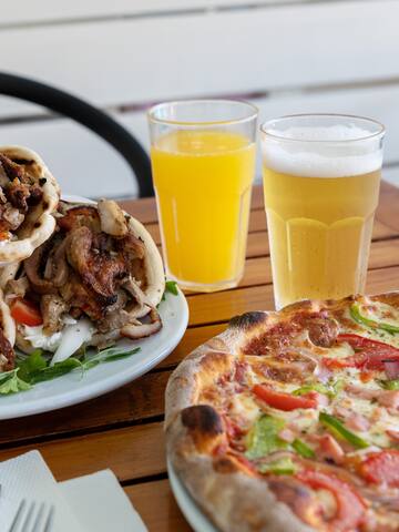 a plate of pizza and two glasses of beer on a table