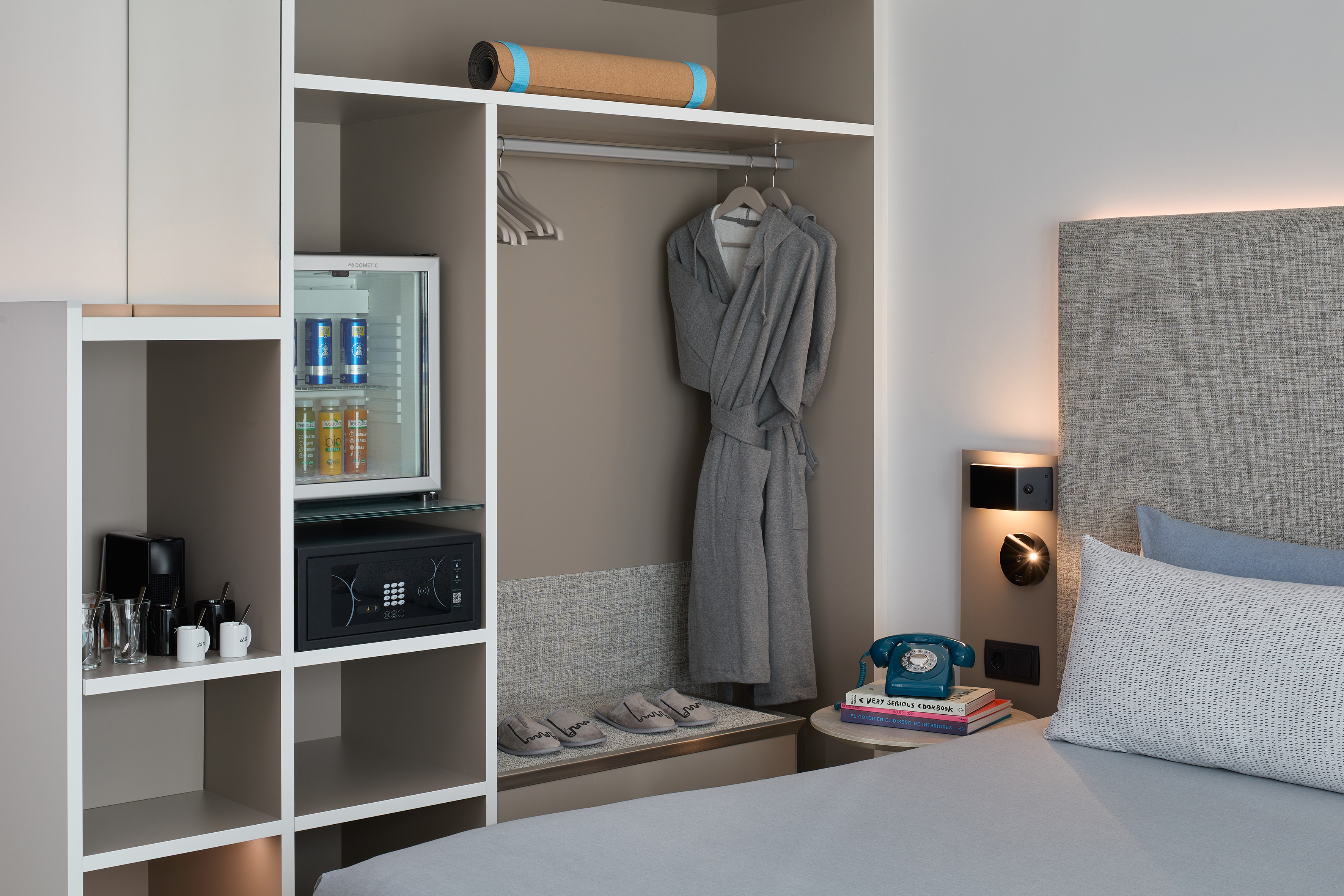 Modern hotel room with wardrobe, mini-bar, coffee setup, safe, and bed.