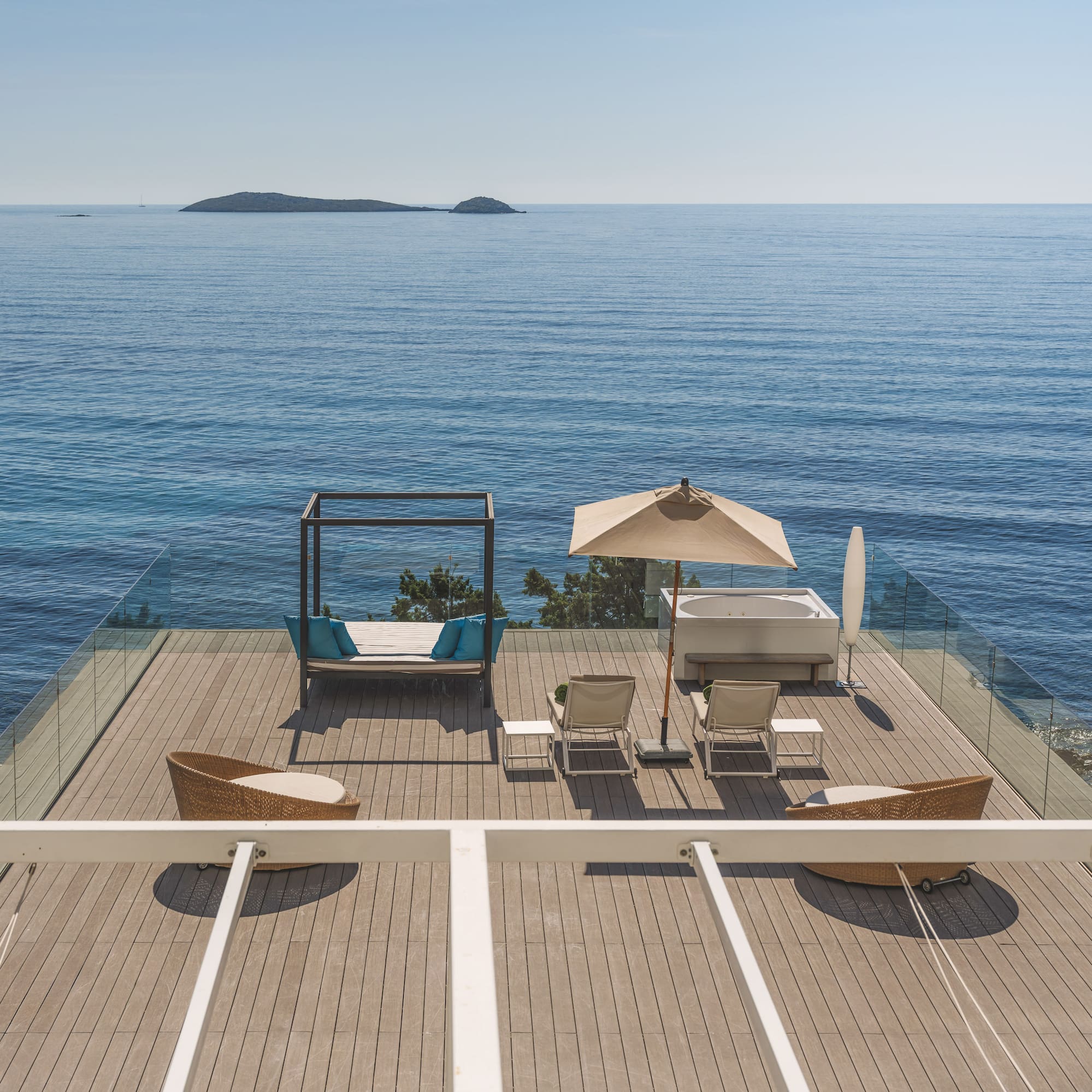 Luxury oceanfront deck with hot tub, daybed, lounge chairs, and islands.
