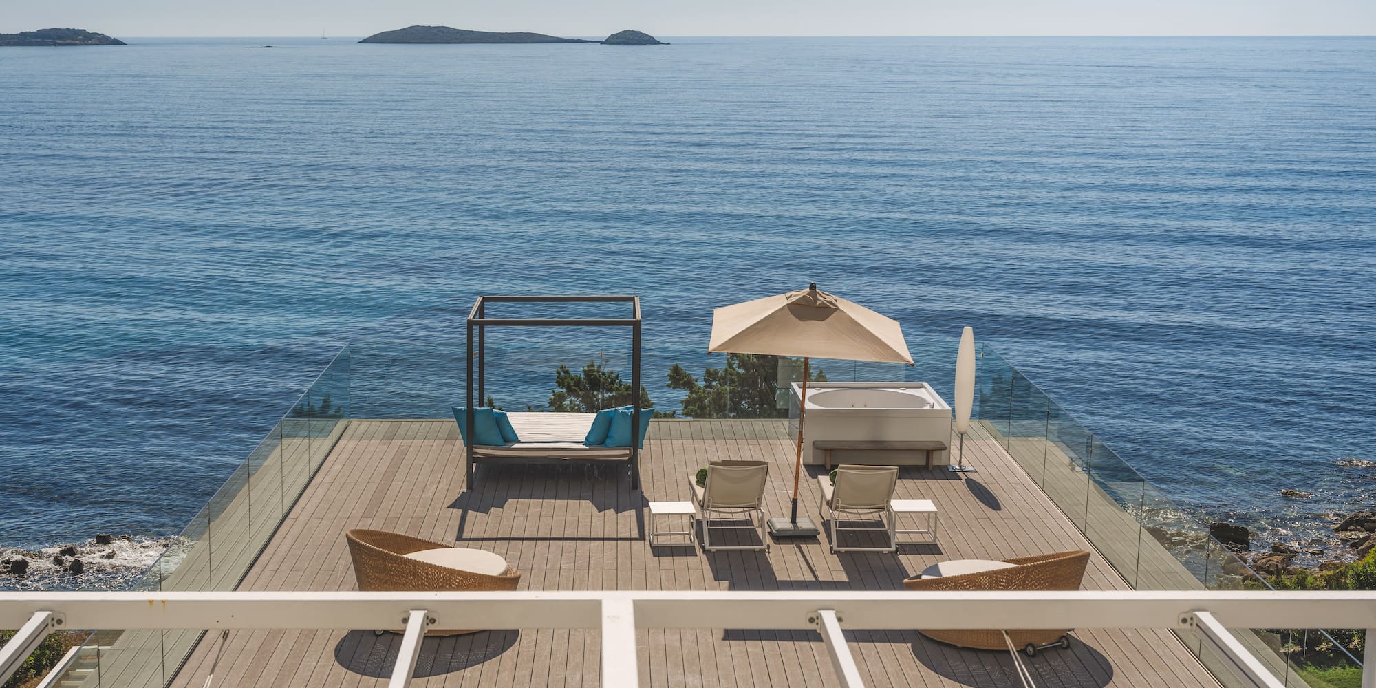 Luxury oceanfront deck with hot tub, daybed, lounge chairs, and islands.