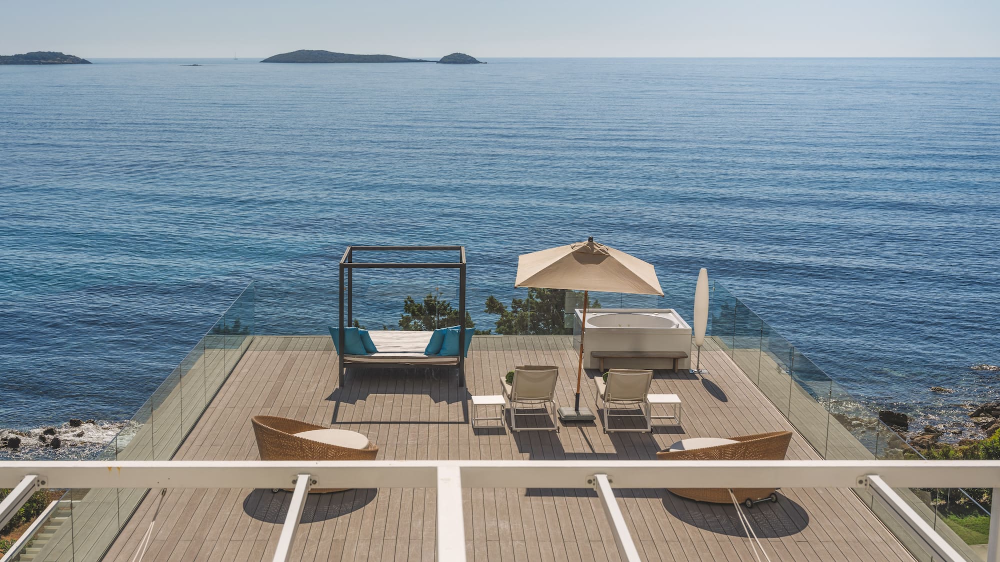 Luxury oceanfront deck with hot tub, daybed, lounge chairs, and islands.