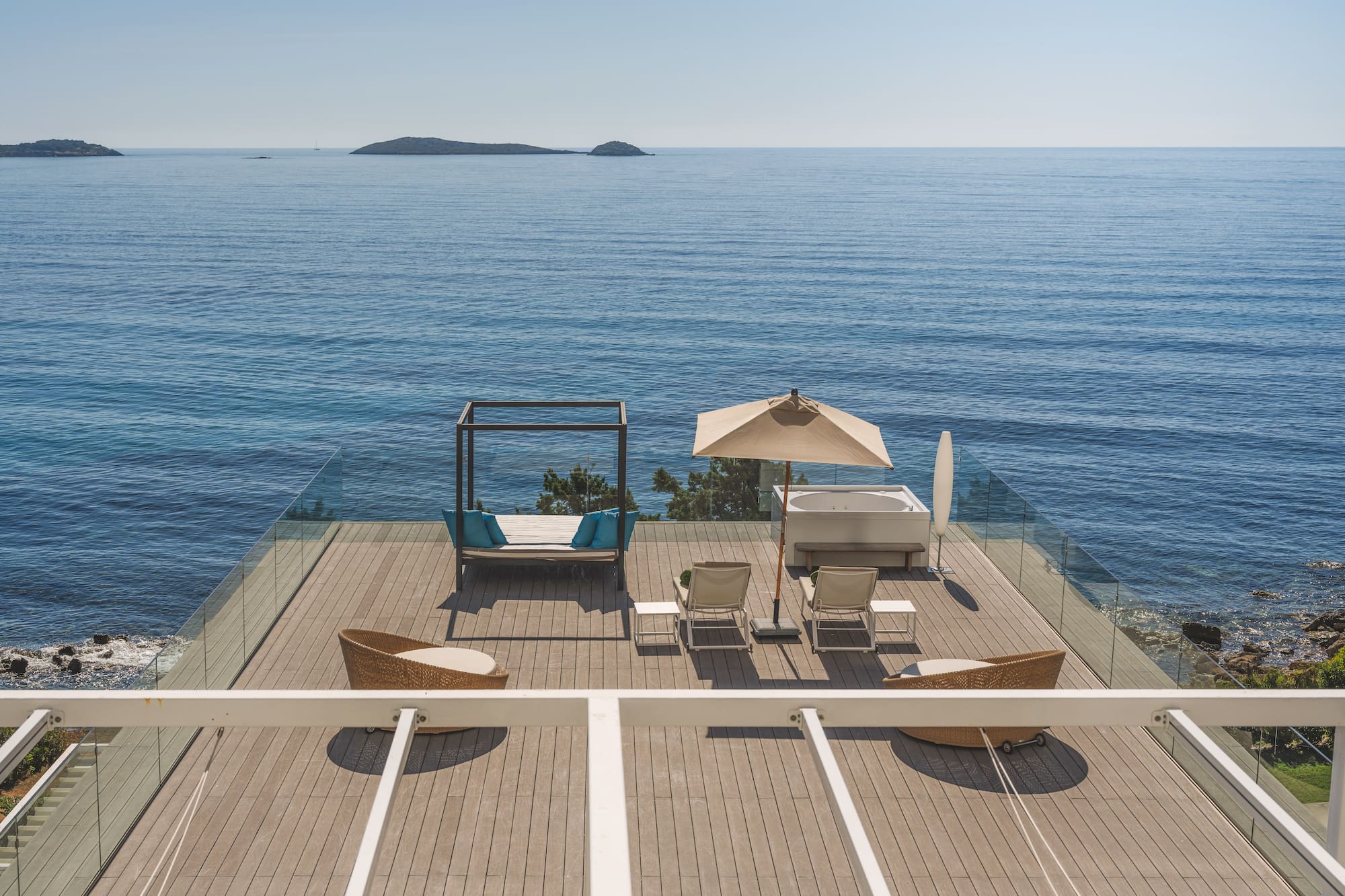 Luxury oceanfront deck with hot tub, daybed, lounge chairs, and islands.
