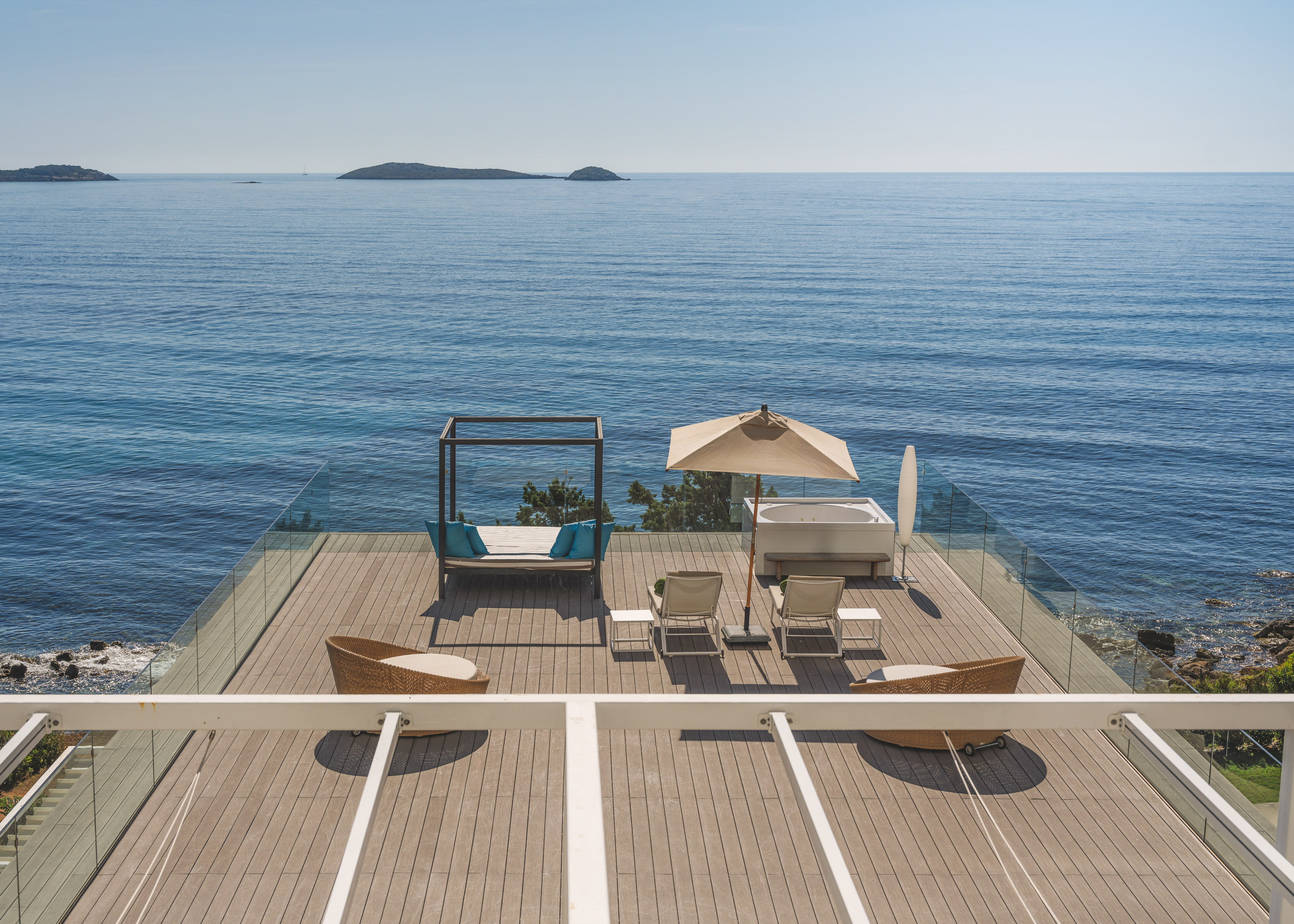 Luxury oceanfront deck with hot tub, daybed, lounge chairs, and islands.