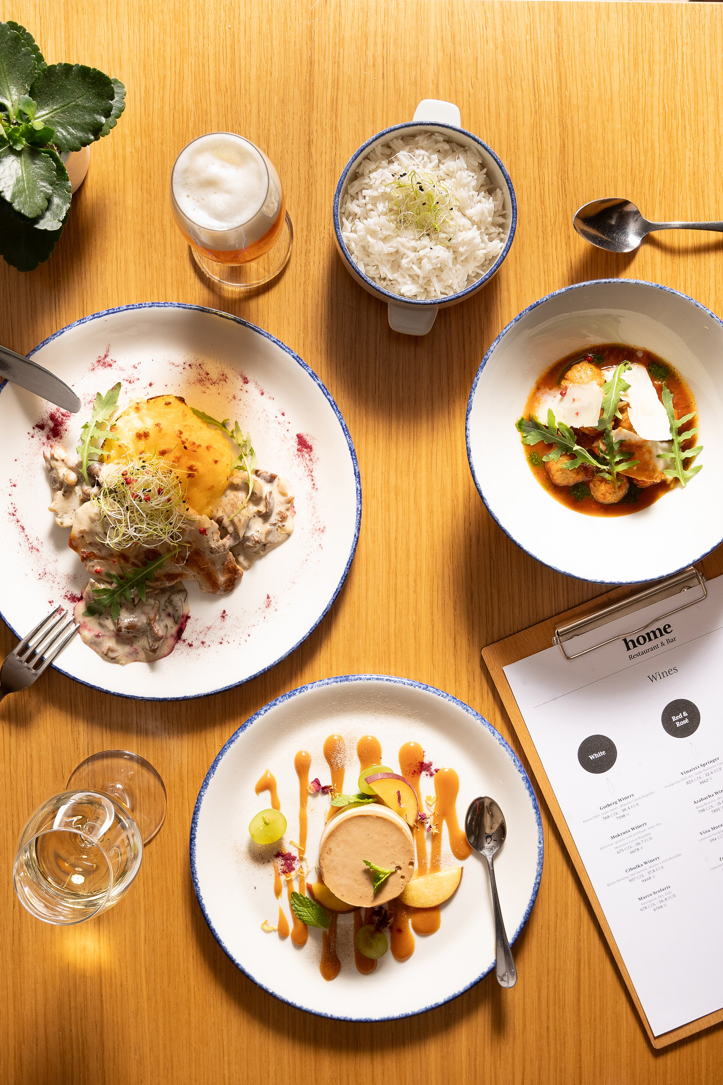 Restaurant dining table: gourmet dishes, rice, beer, white wine, and wine list.