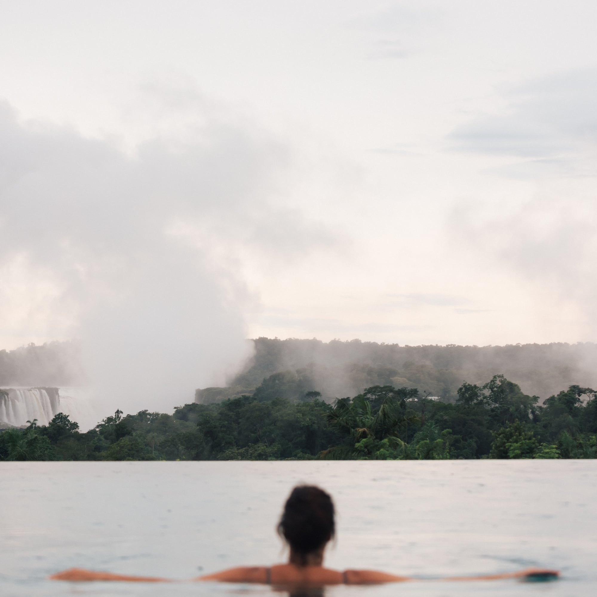 a woman in a pool with a waterfall in the background