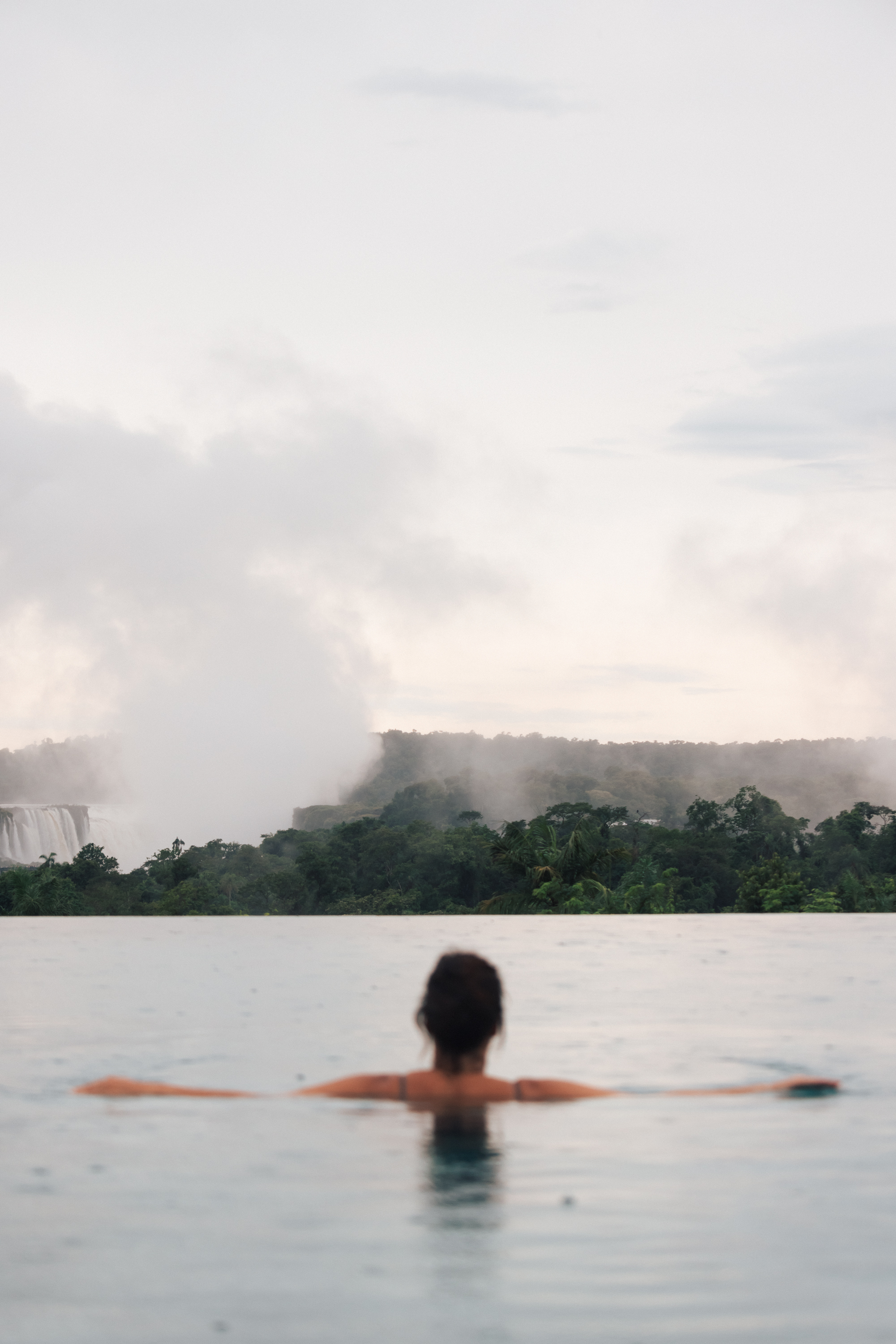 a woman in a pool with a waterfall in the background