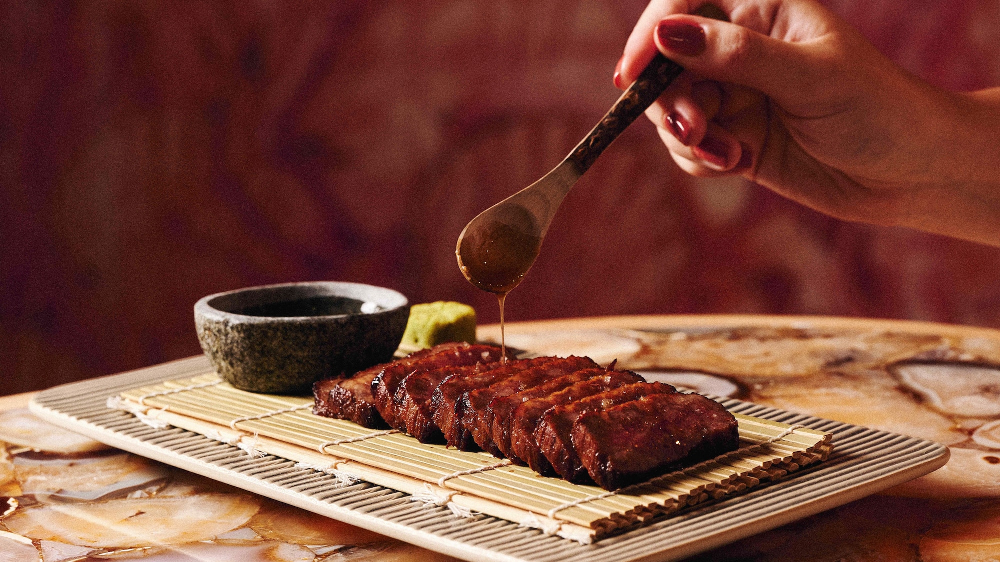a person pouring sauce on meat