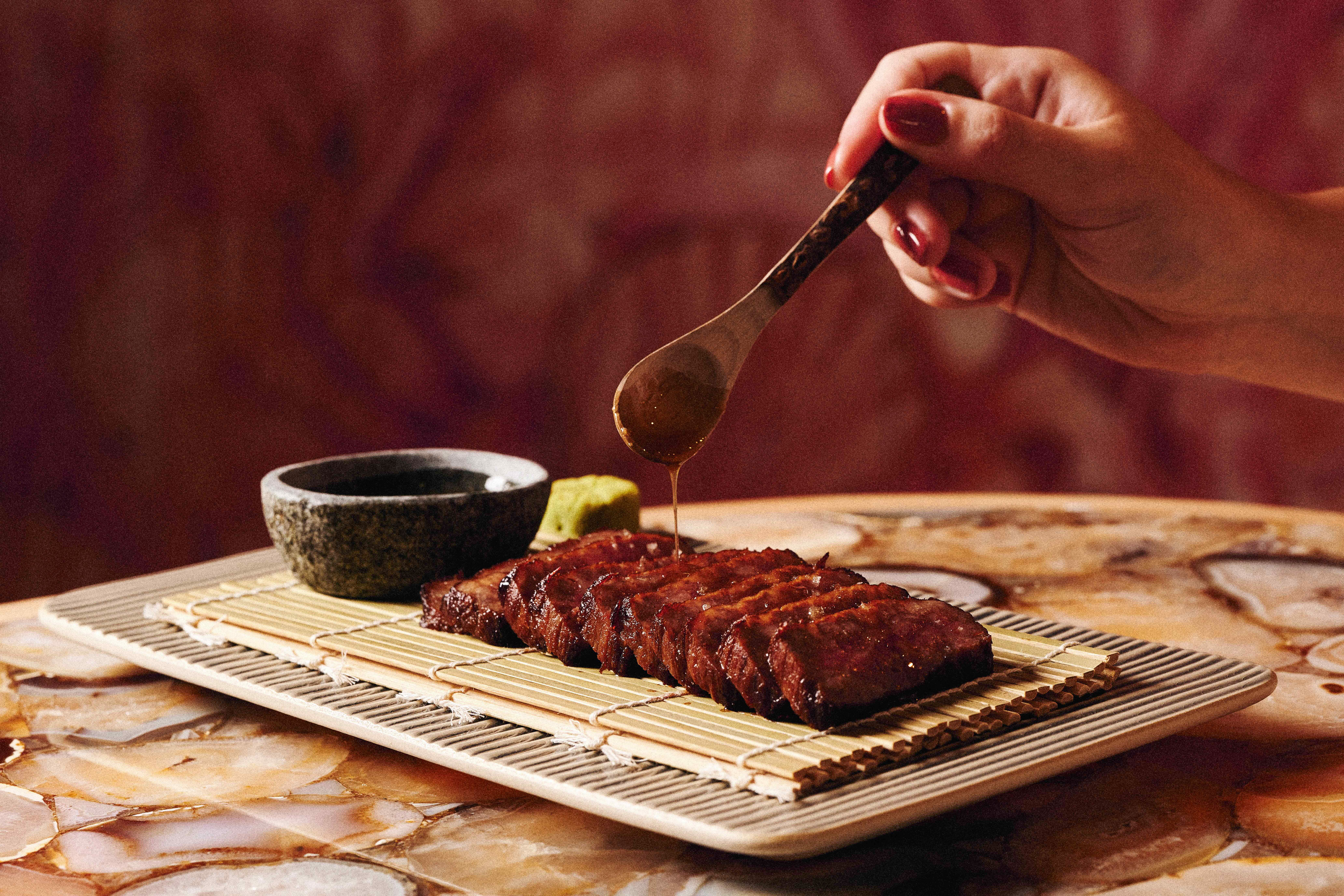 a person pouring sauce on meat