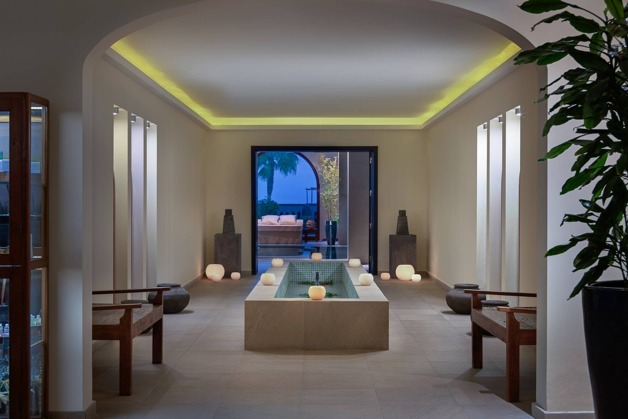 Tranquil spa interior with indoor fountain, ambient lighting, and wooden benches.