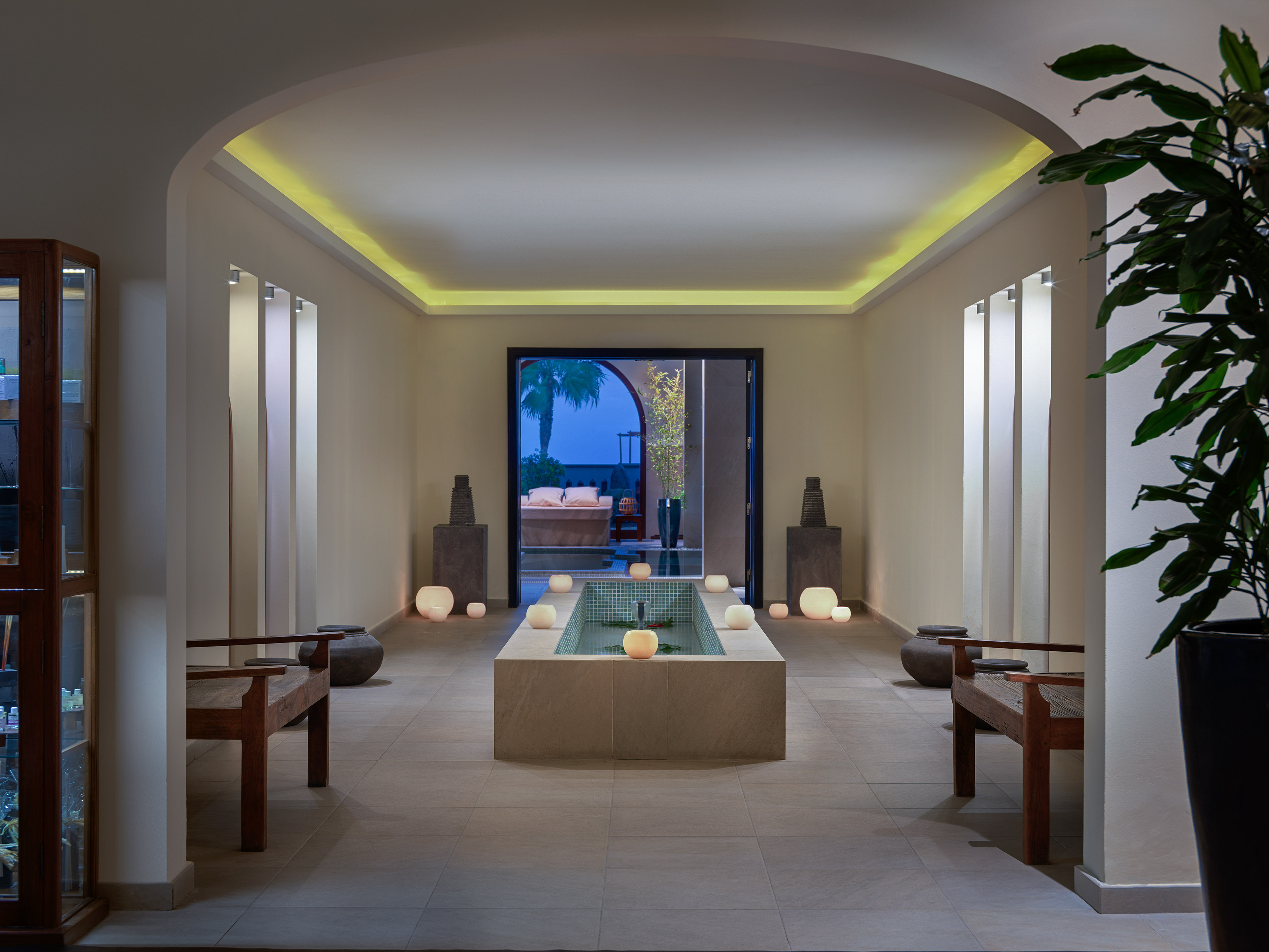 Tranquil spa interior with indoor fountain, ambient lighting, and wooden benches.
