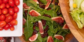 a bowl of salad with figs and tomatoes
