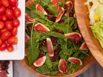 a bowl of salad with figs and tomatoes