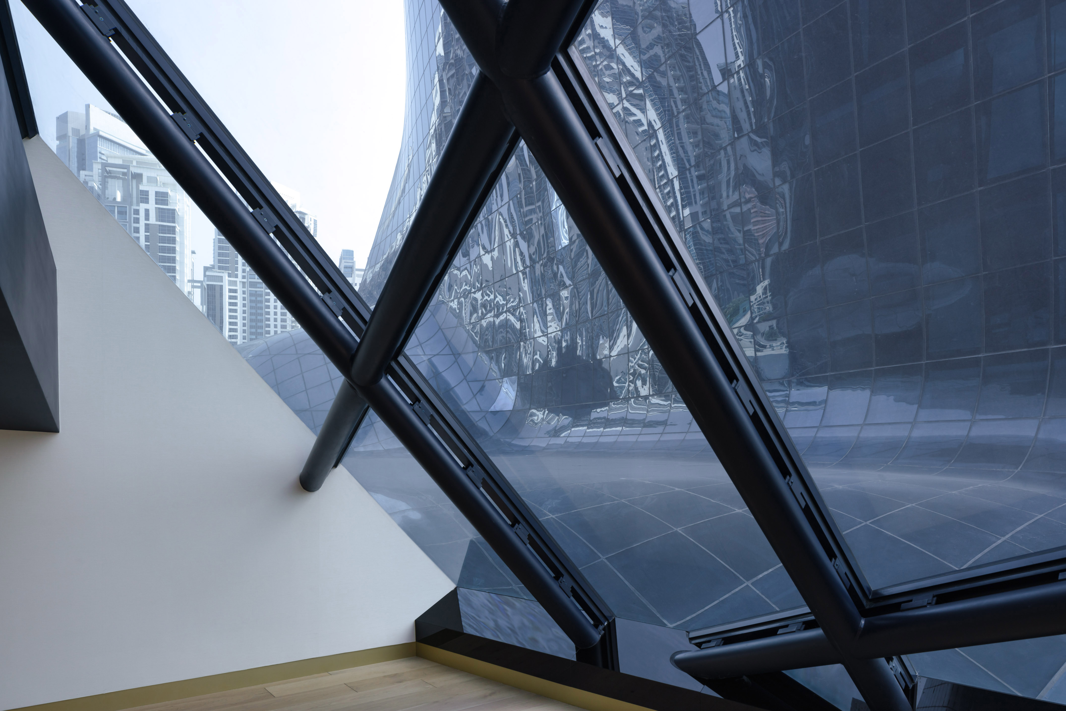 Modern architecture: diagonal black frames, curved glass facade, urban skyline.