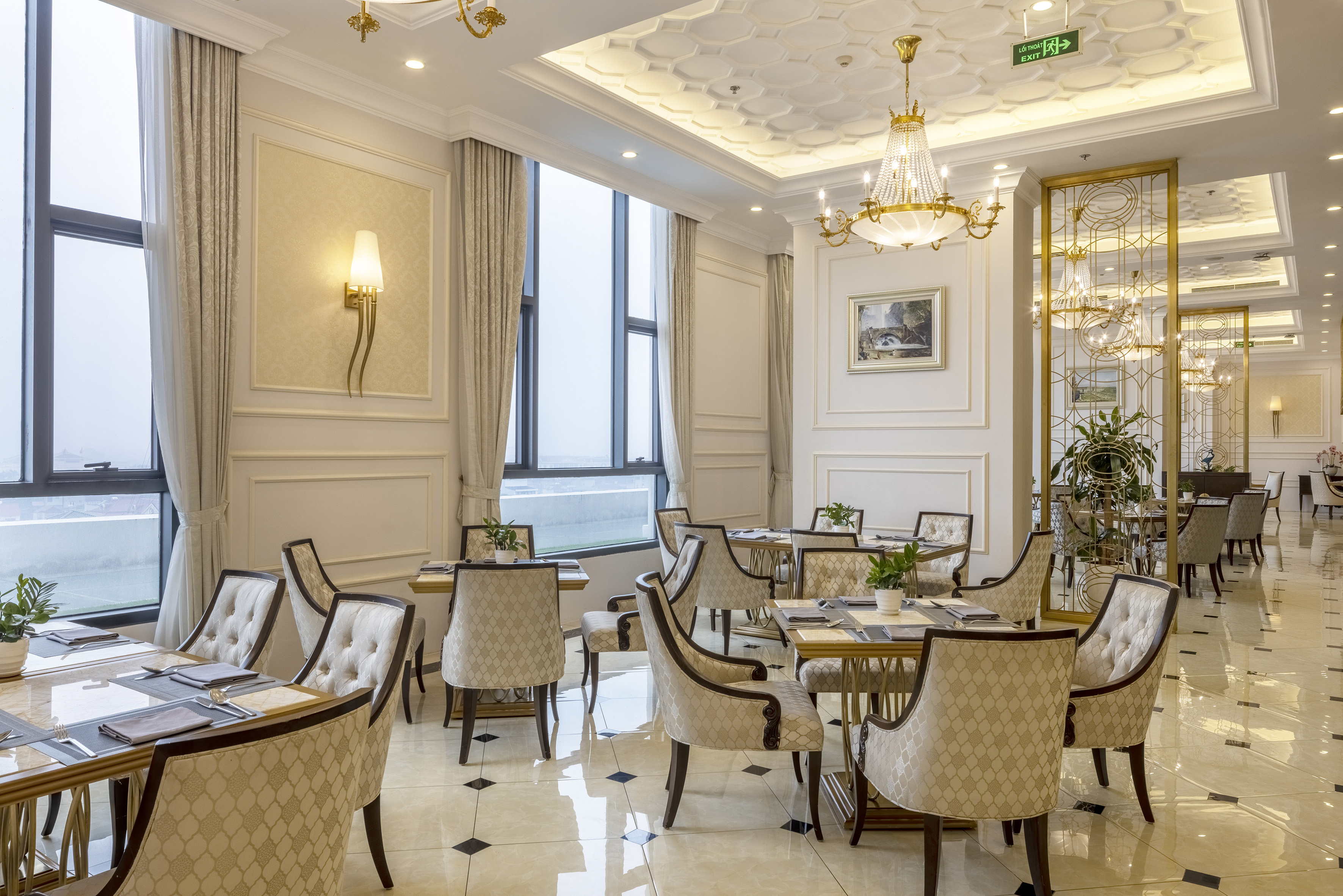 Elegant restaurant with chandeliers, large windows, and set dining tables.
