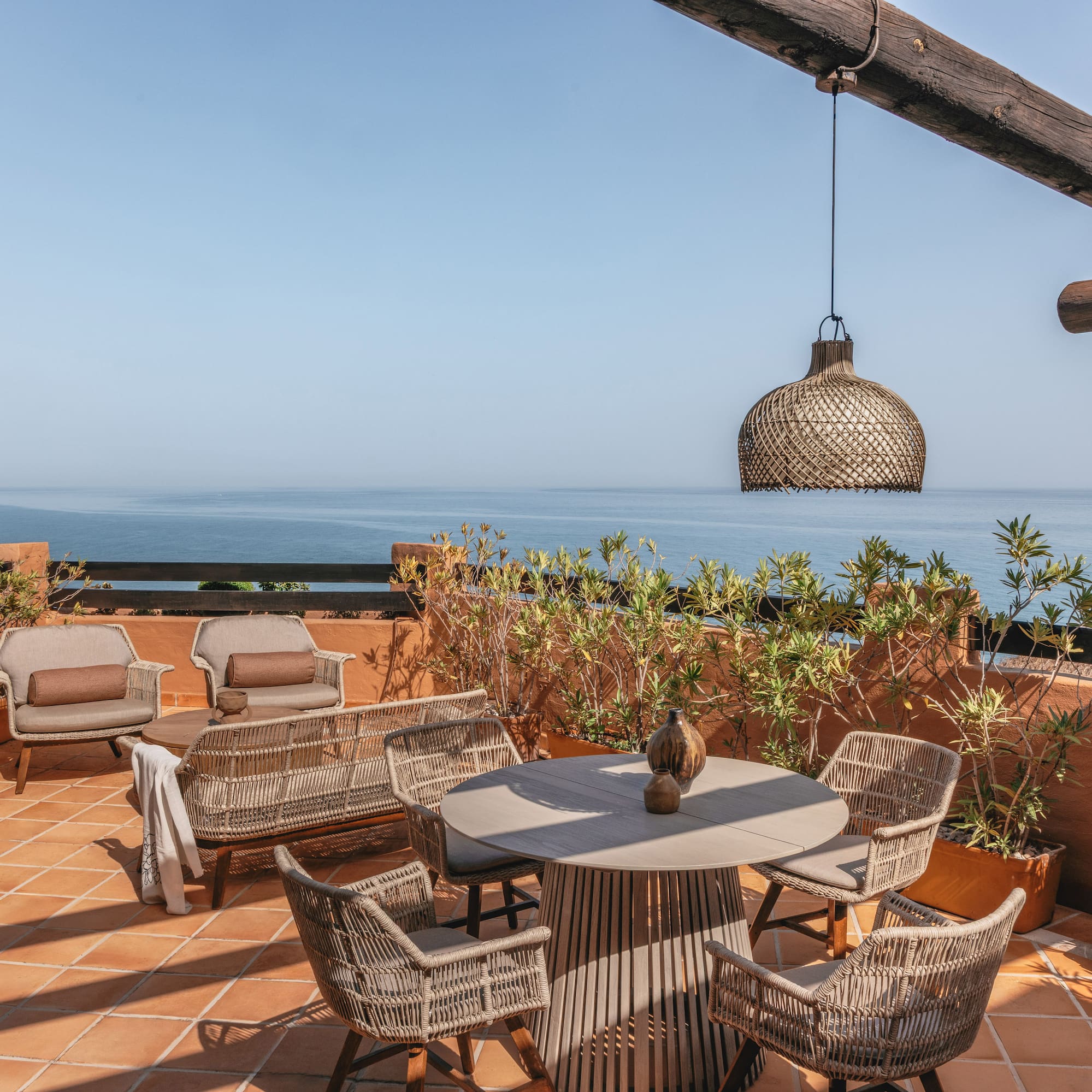Rooftop terrace overlooking blue ocean with stylish outdoor seating.