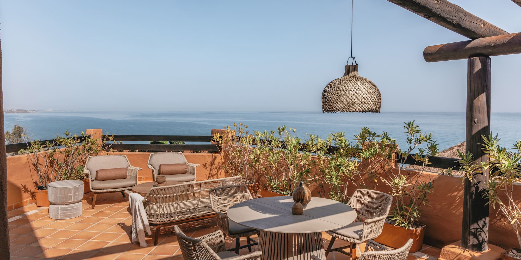 Rooftop terrace overlooking blue ocean with stylish outdoor seating.