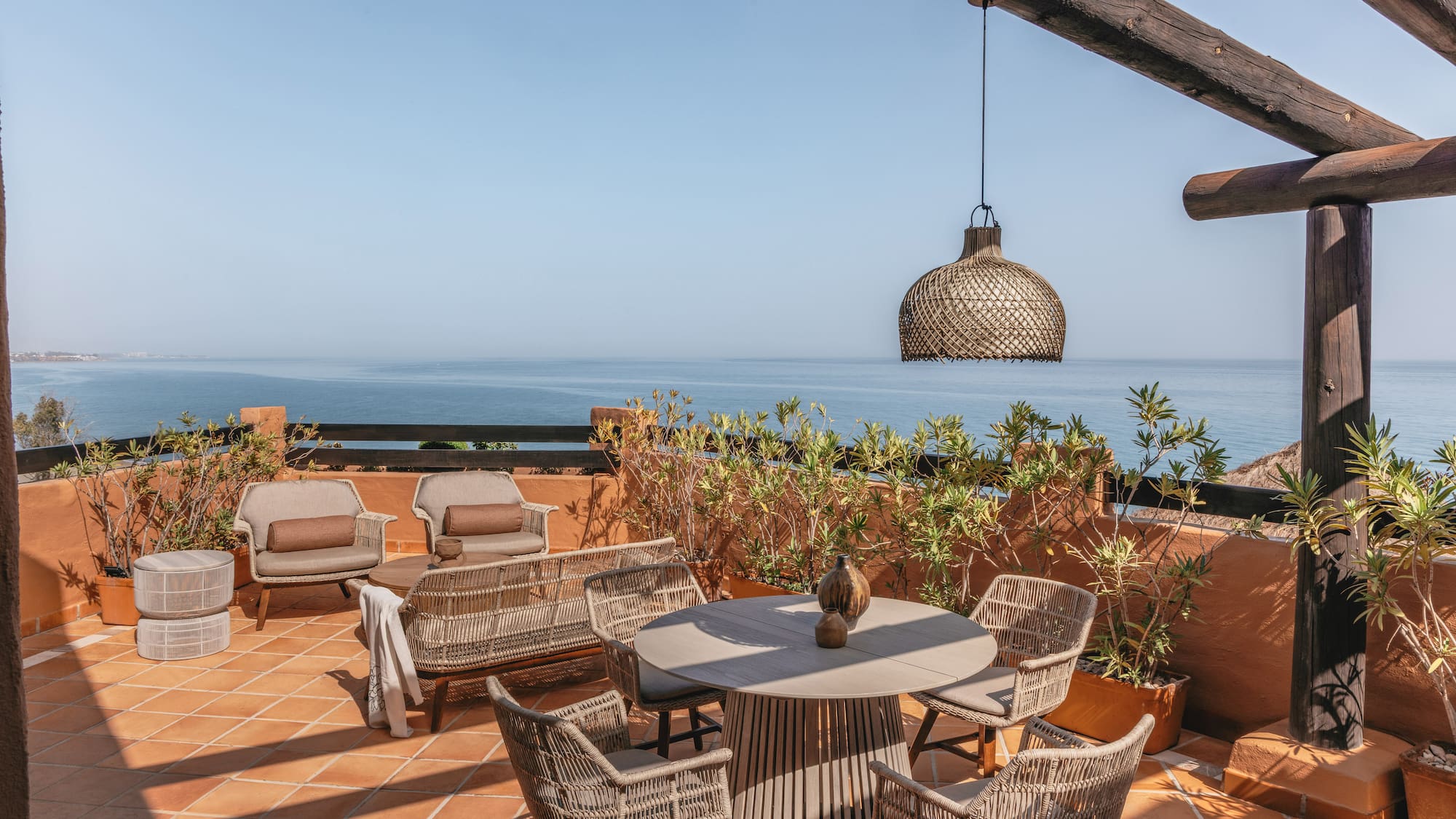 Rooftop terrace overlooking blue ocean with stylish outdoor seating.