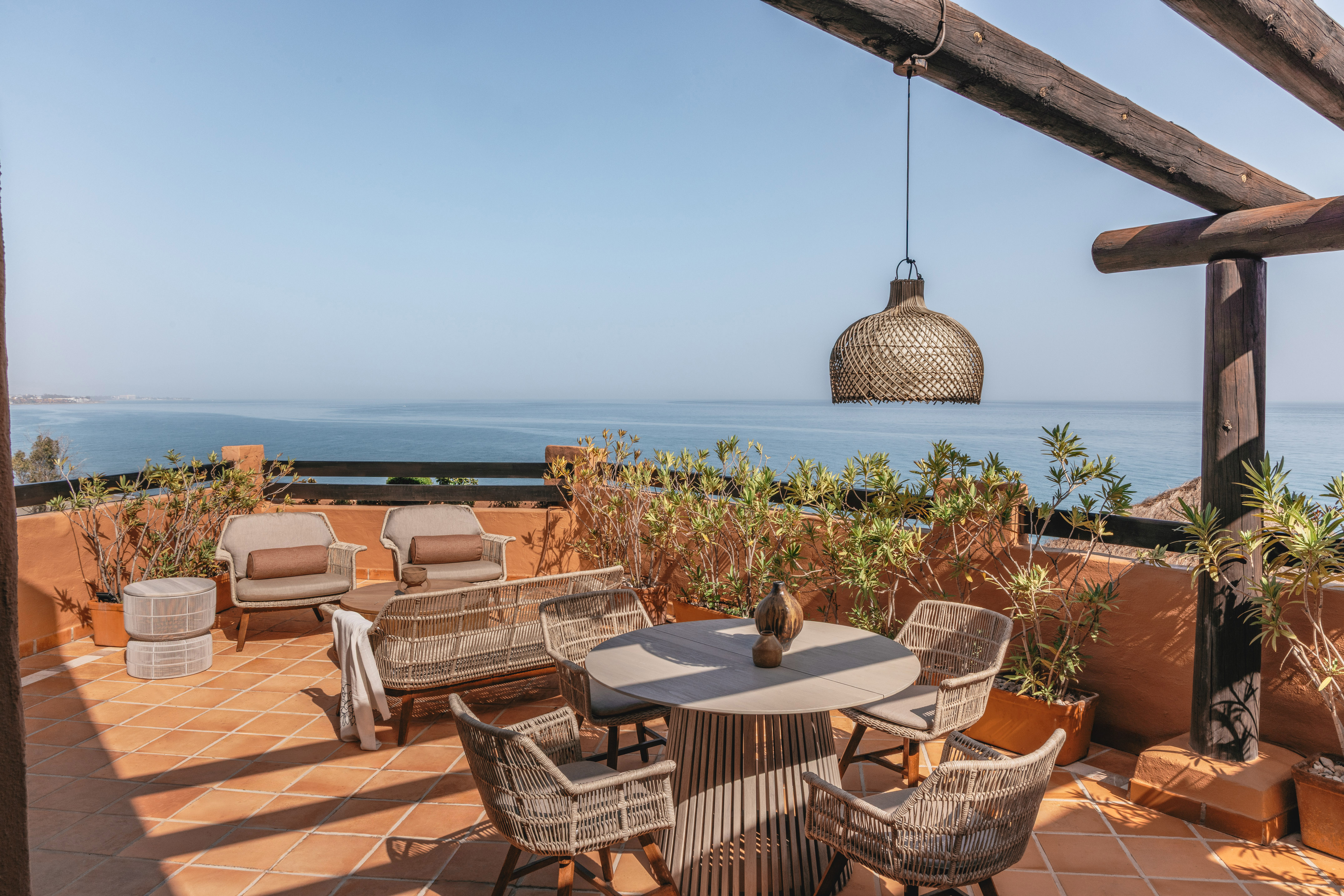 Rooftop terrace overlooking blue ocean with stylish outdoor seating.