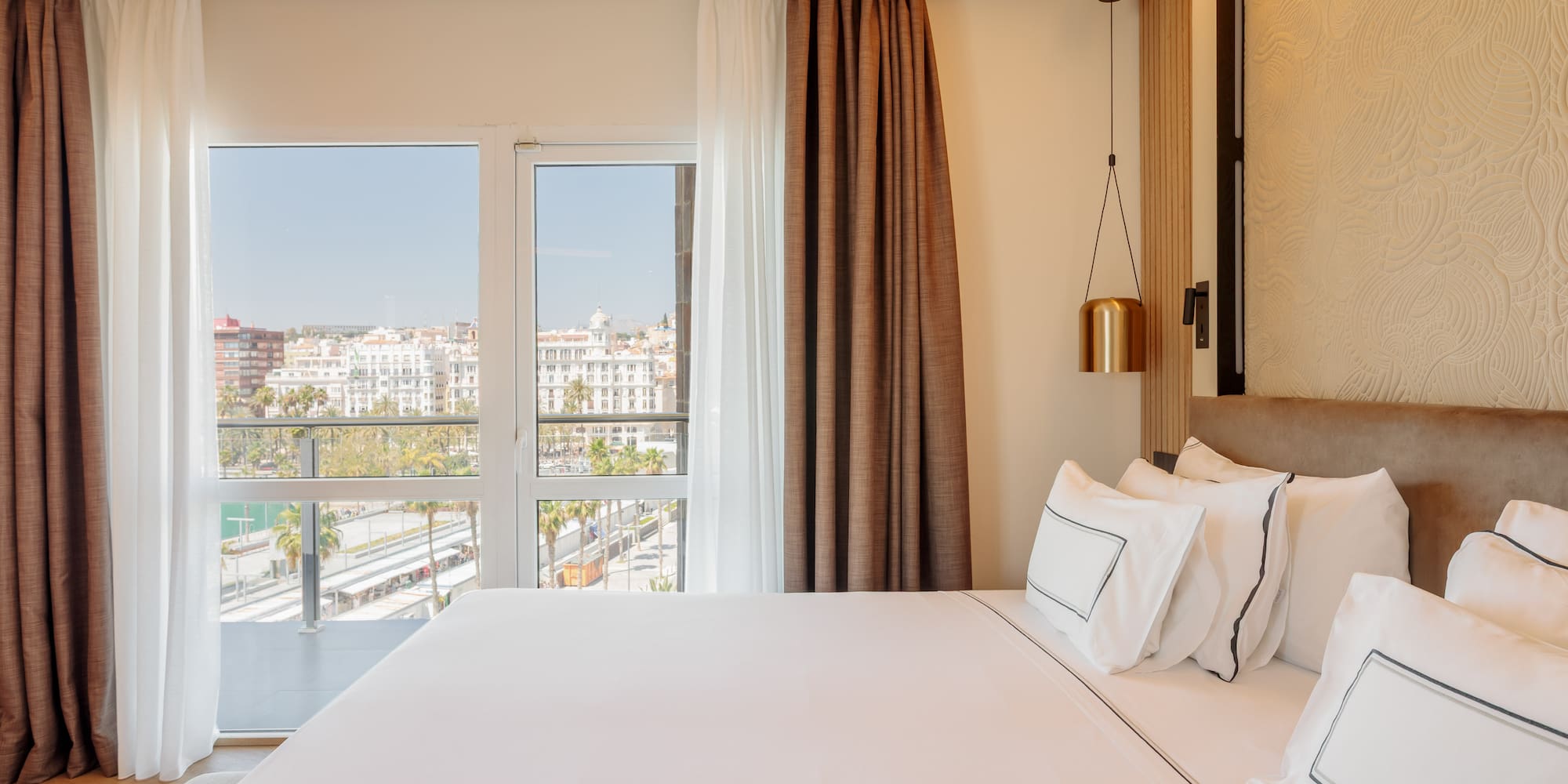a bed with white sheets and brown curtains