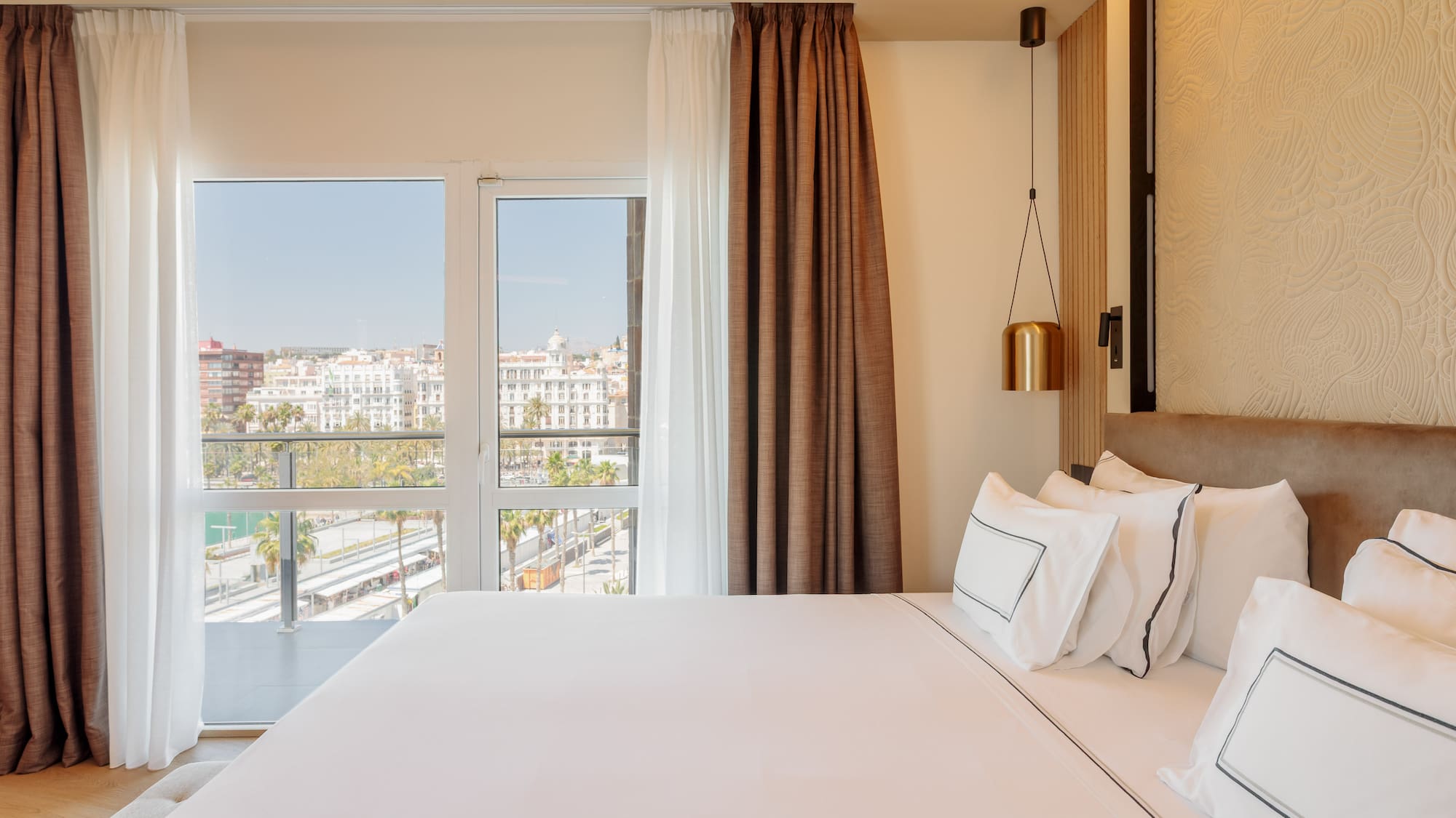 a bed with white sheets and brown curtains