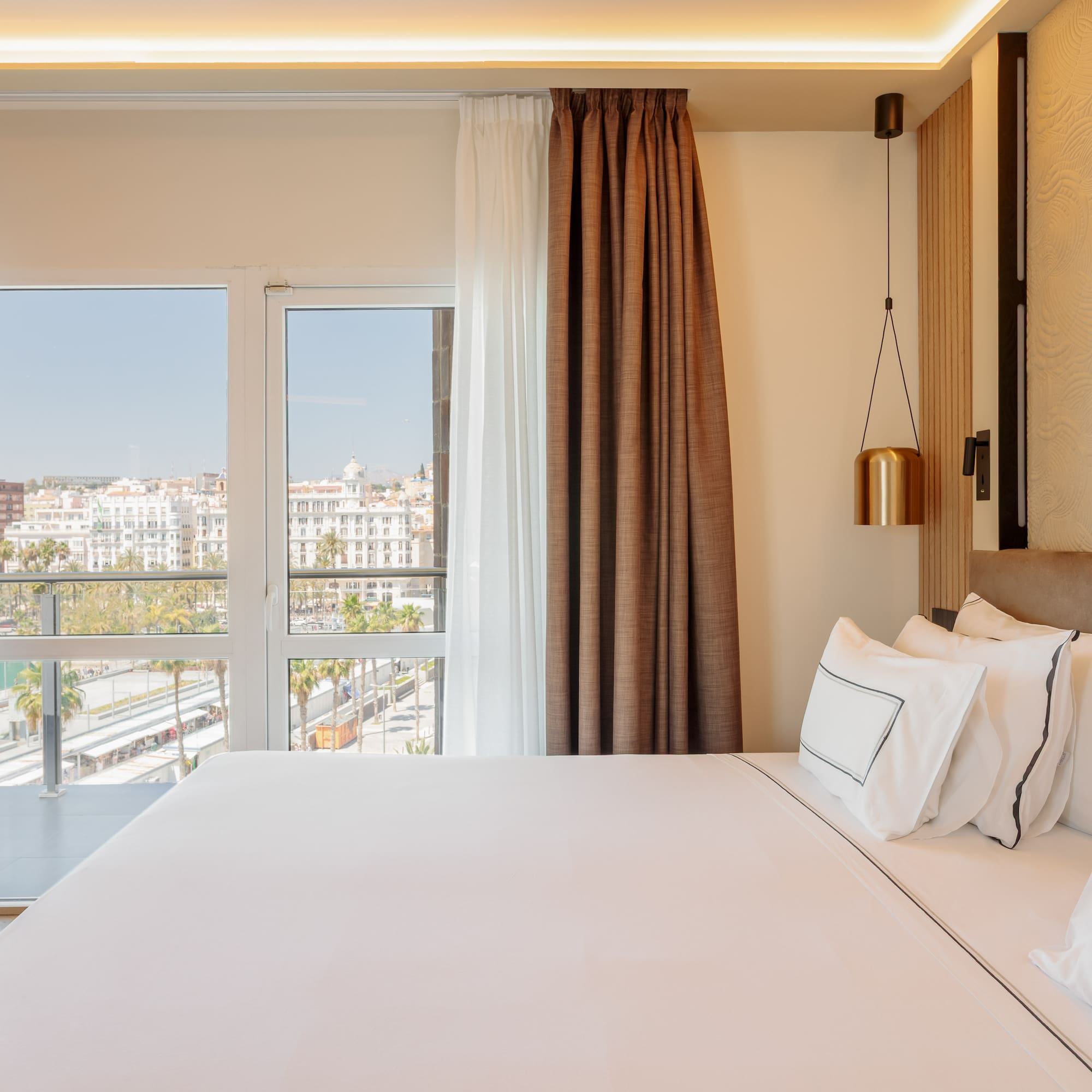 a bed with white sheets and brown curtains