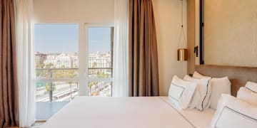 a bed with white sheets and brown curtains