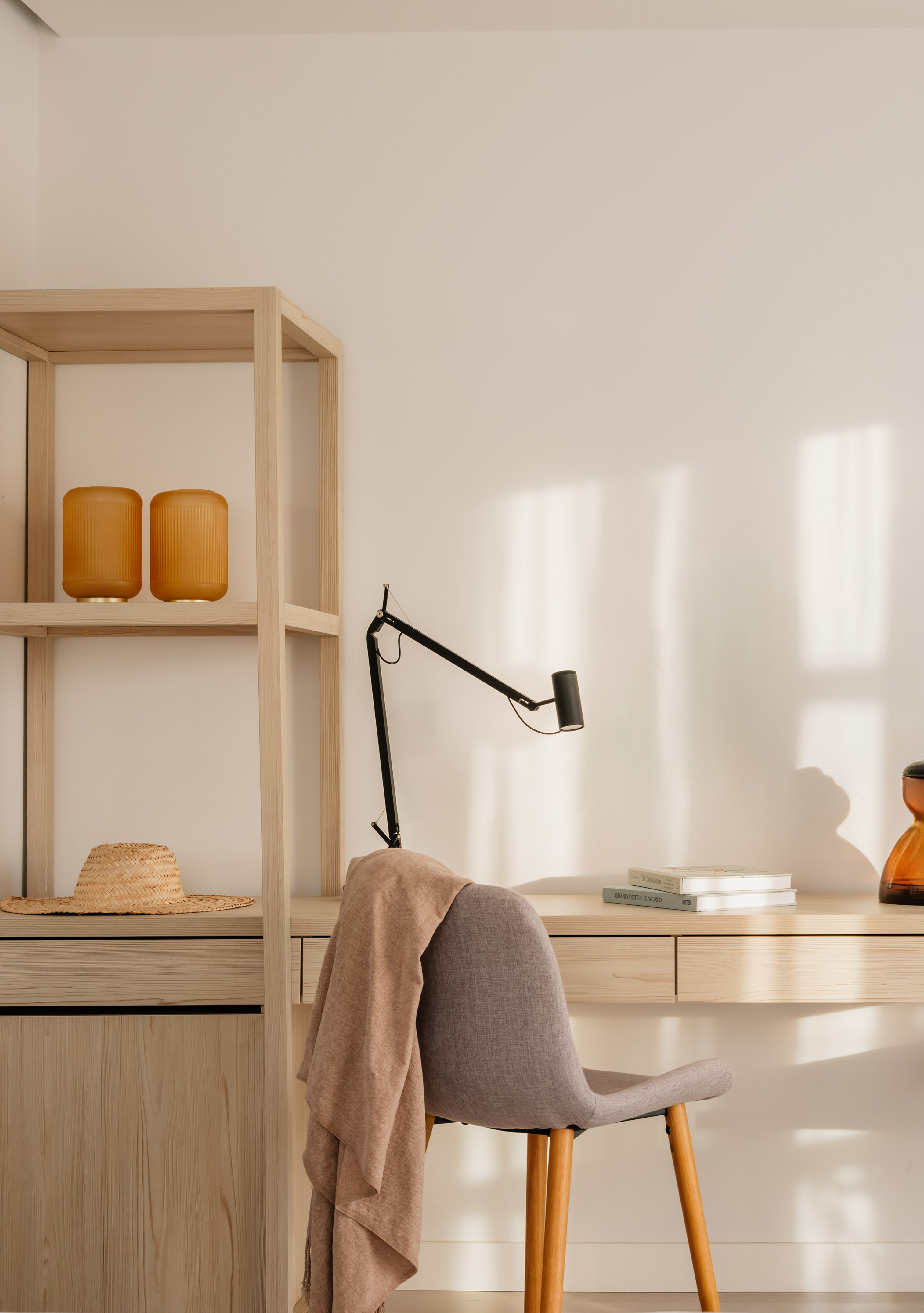 Oficina en casa luminosa: escritorio madera, silla, lámpara y estantería.