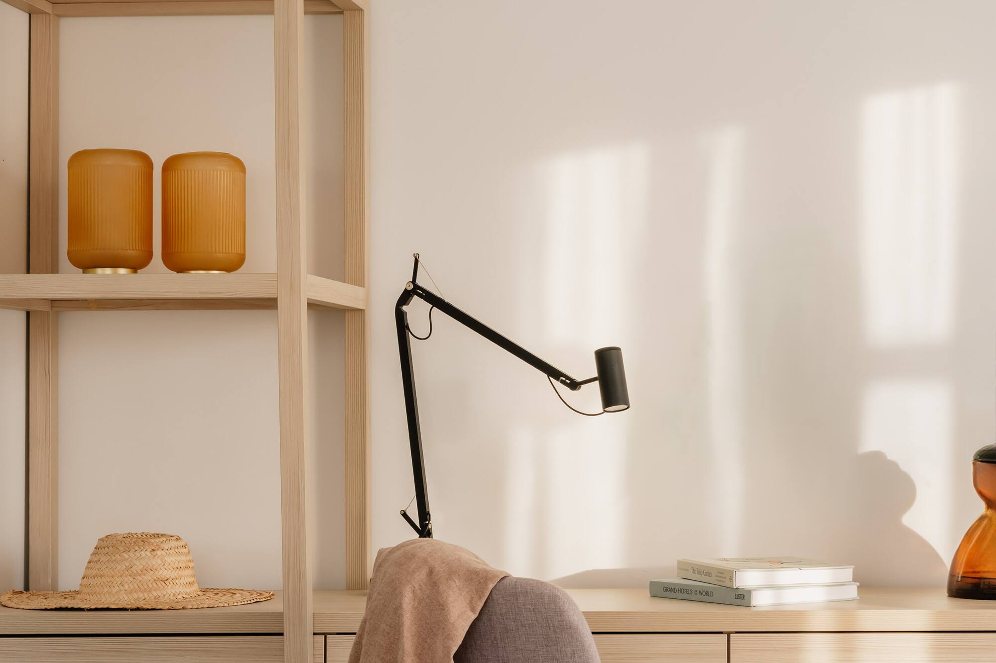 Oficina en casa luminosa: escritorio madera, silla, lámpara y estantería.