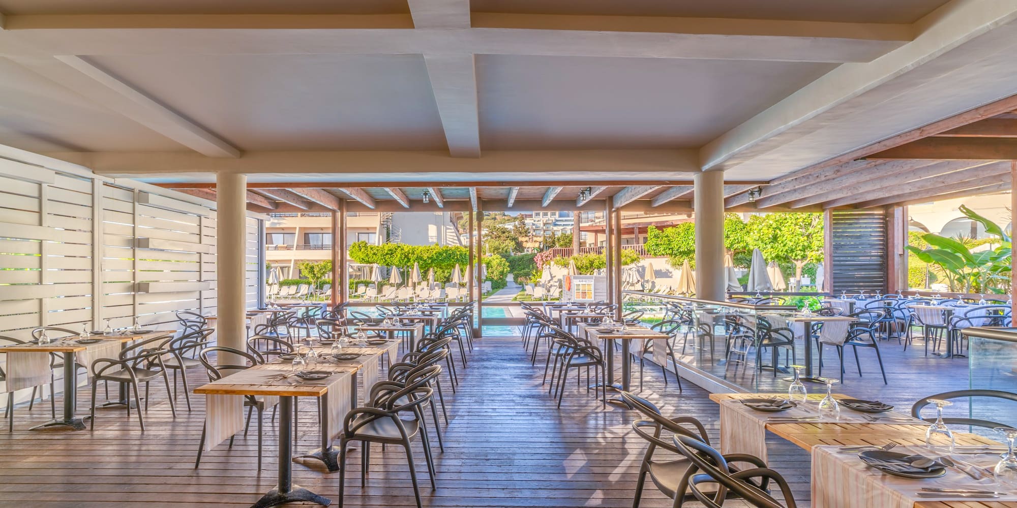 Modern resort outdoor dining area overlooking a swimming pool.