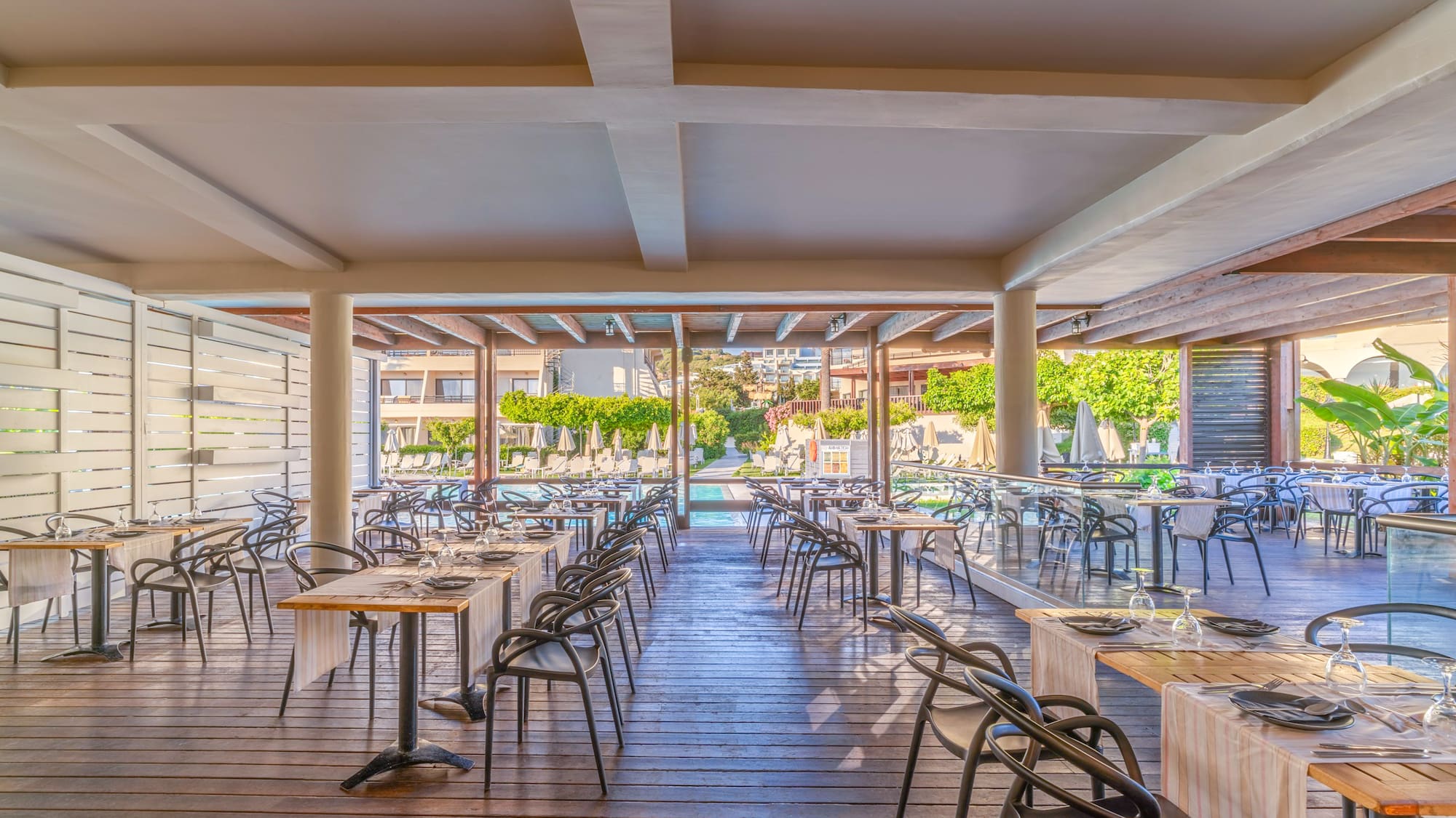 Modern resort outdoor dining area overlooking a swimming pool.