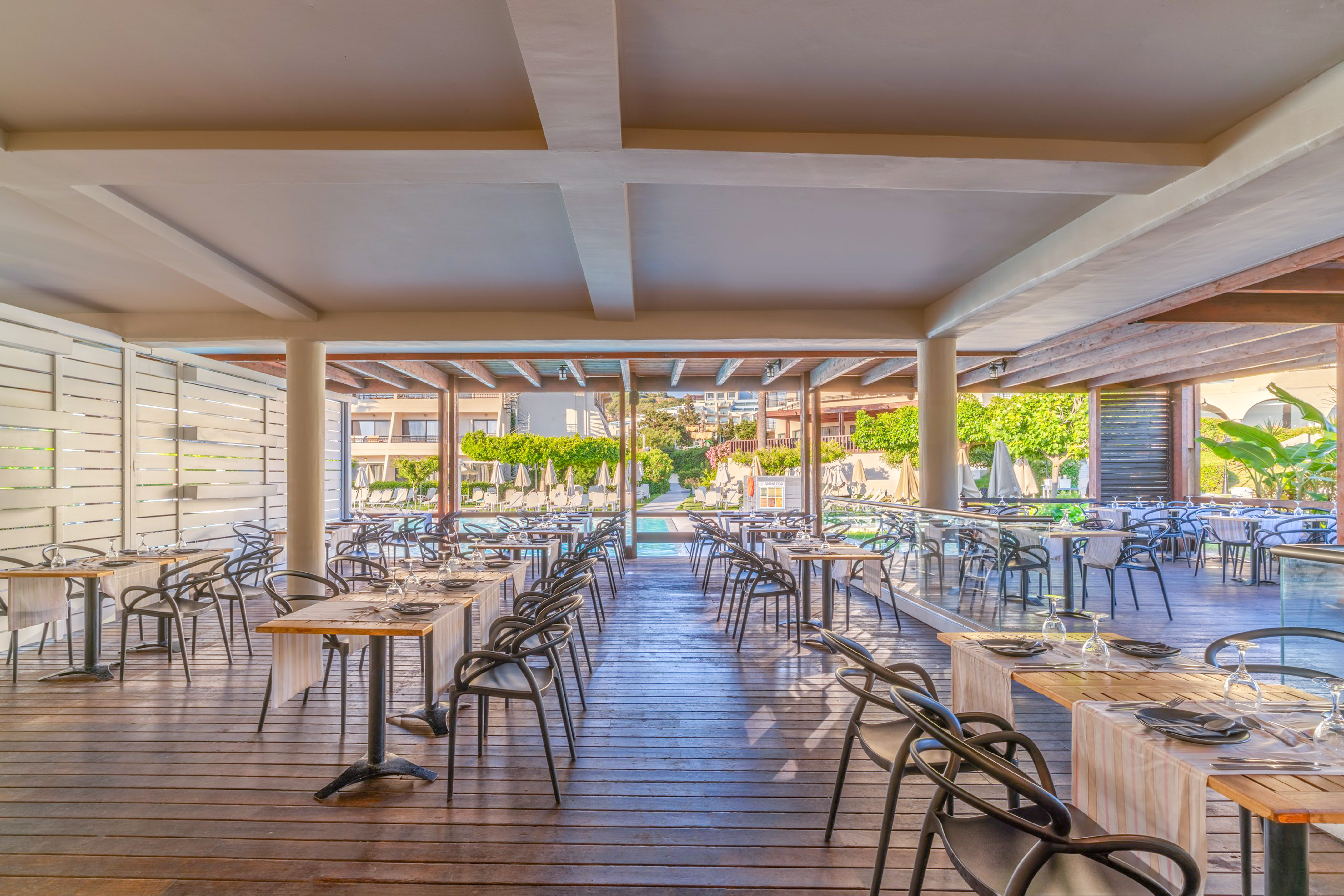 Modern resort outdoor dining area overlooking a swimming pool.