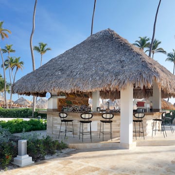 a bar with stools and chairs on a beach