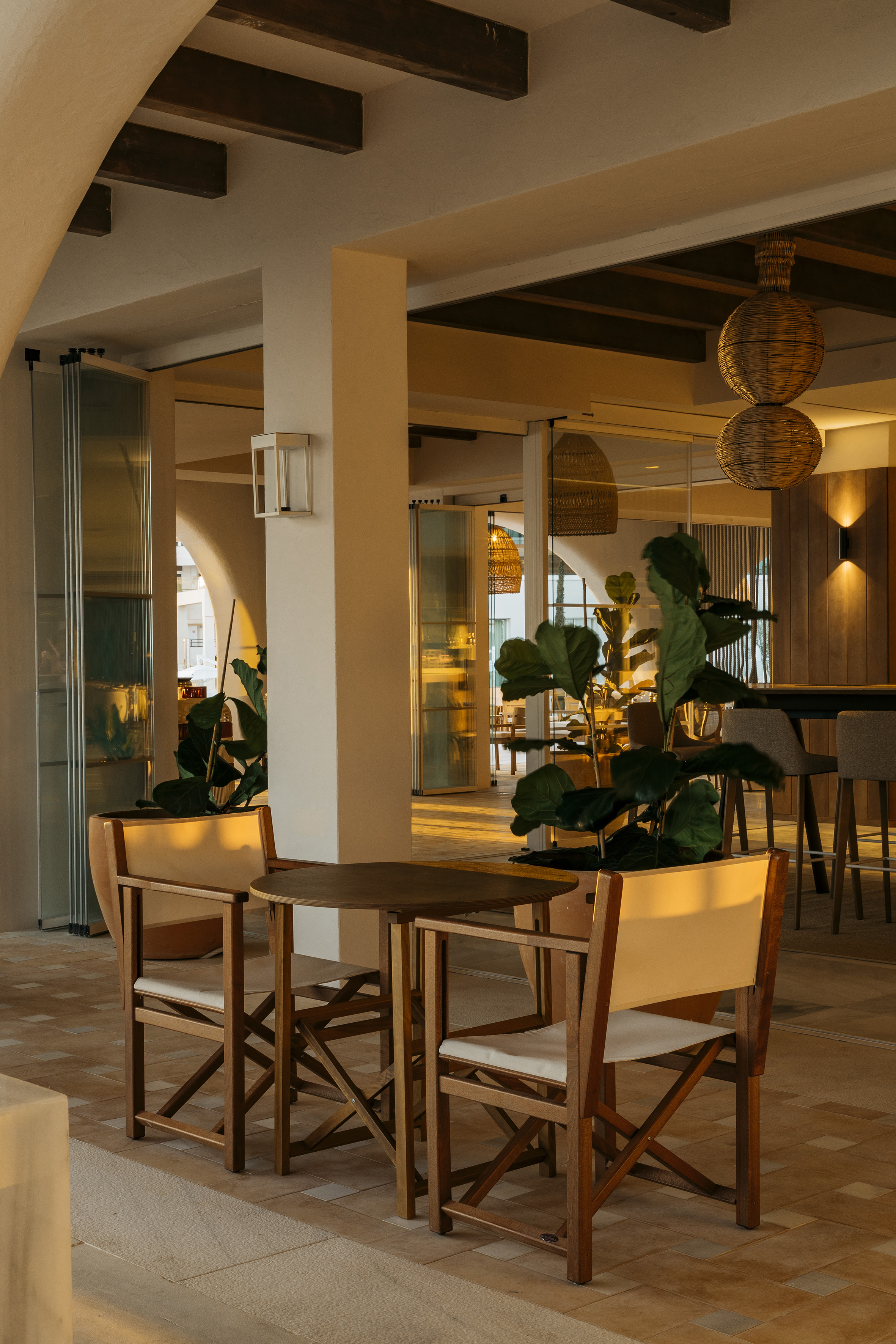 Inviting cafe patio with wooden chairs, potted plant, and warm golden lighting.