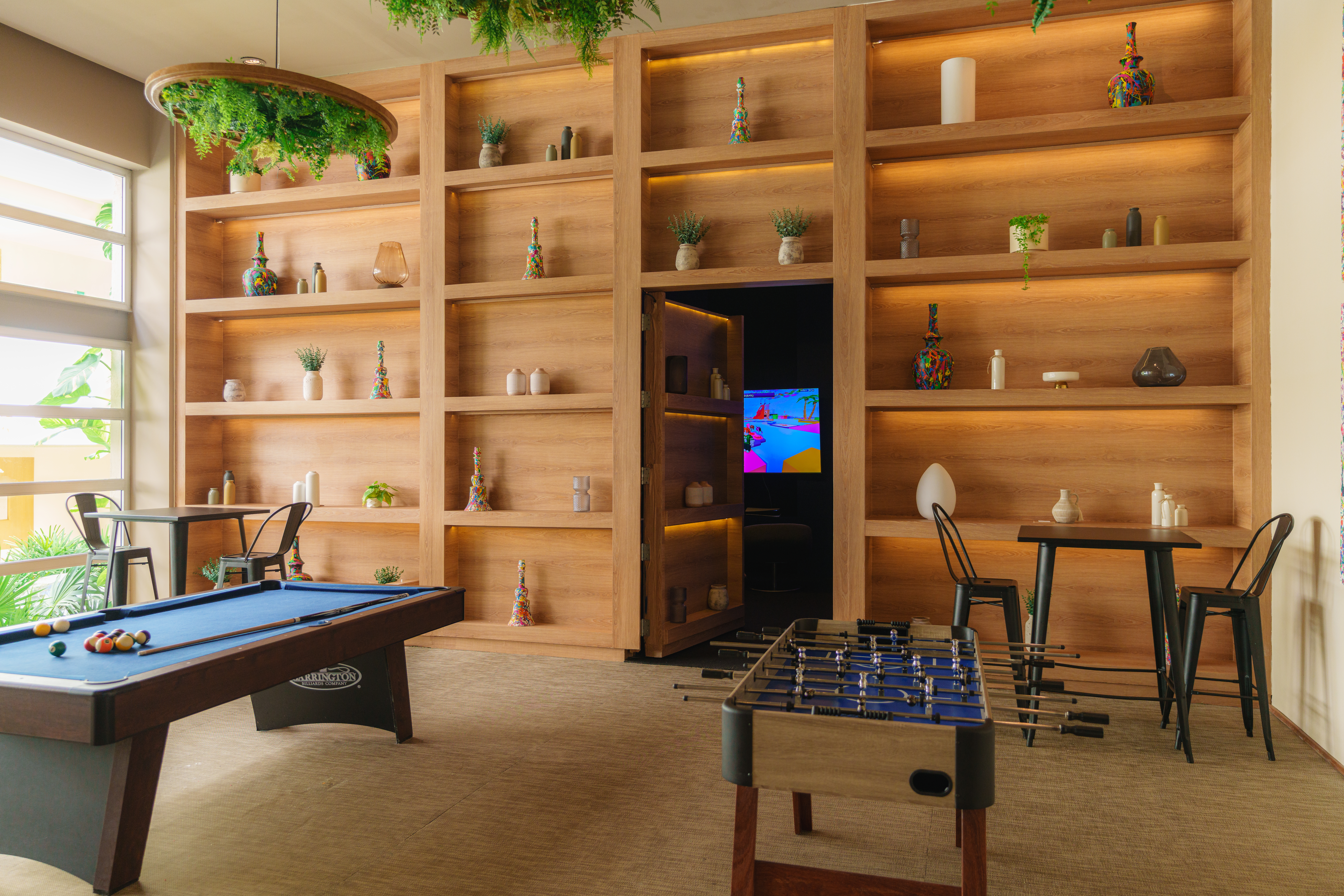 Modern game room with pool table, foosball, and decorative wooden shelves.