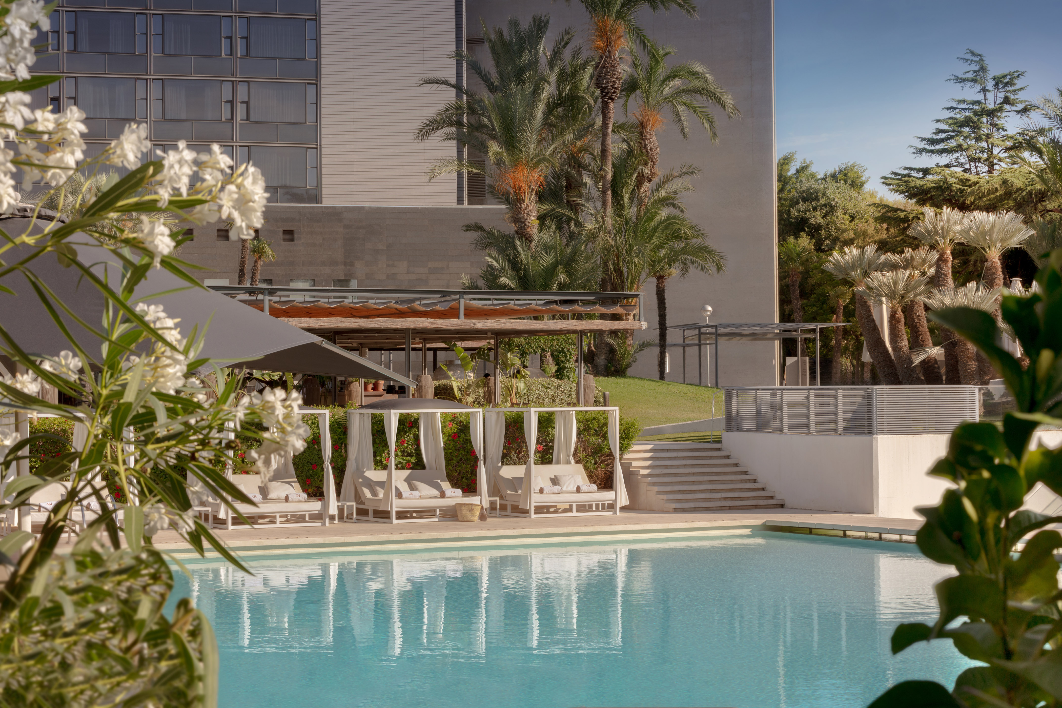 Luxury resort pool with white cabanas, palm trees, and modern hotel.