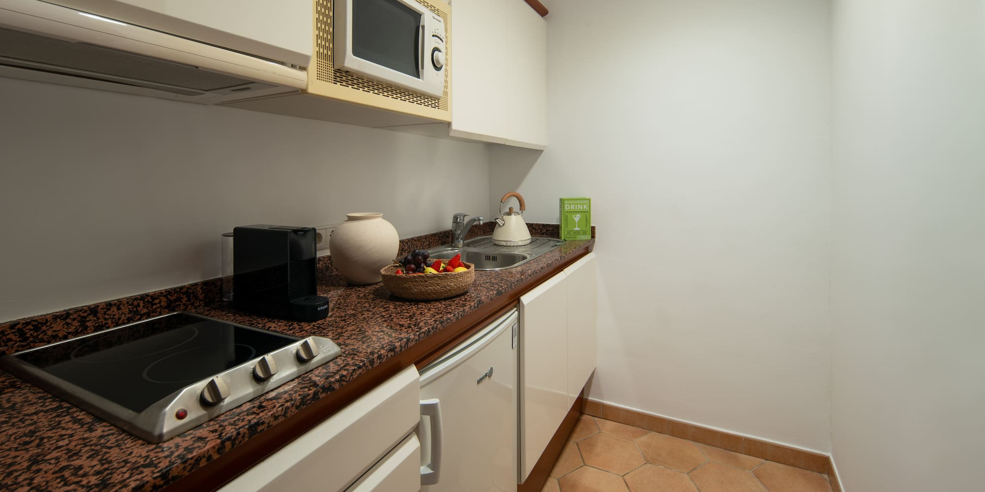 a kitchen with white cabinets and a bowl of fruit on a counter top