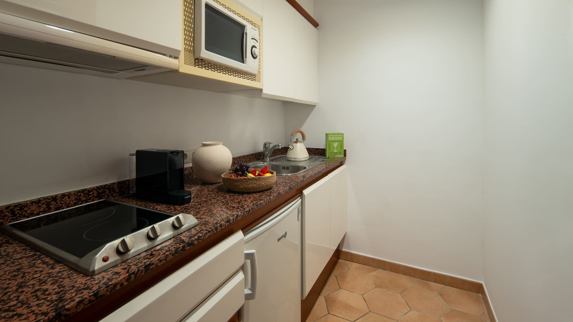 a kitchen with white cabinets and a bowl of fruit on a counter top