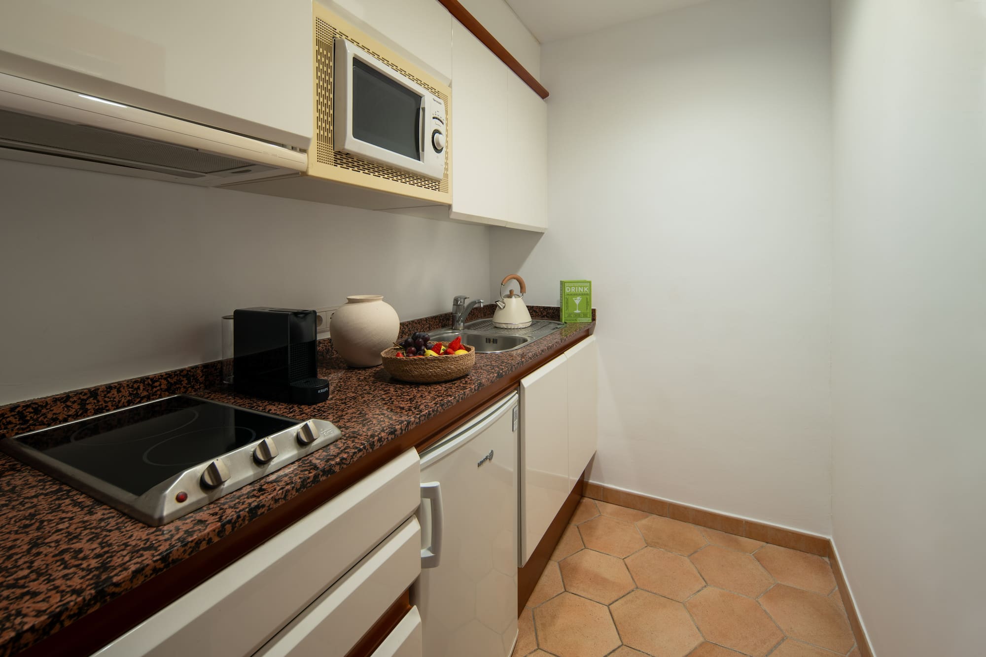 a kitchen with white cabinets and a bowl of fruit on a counter top