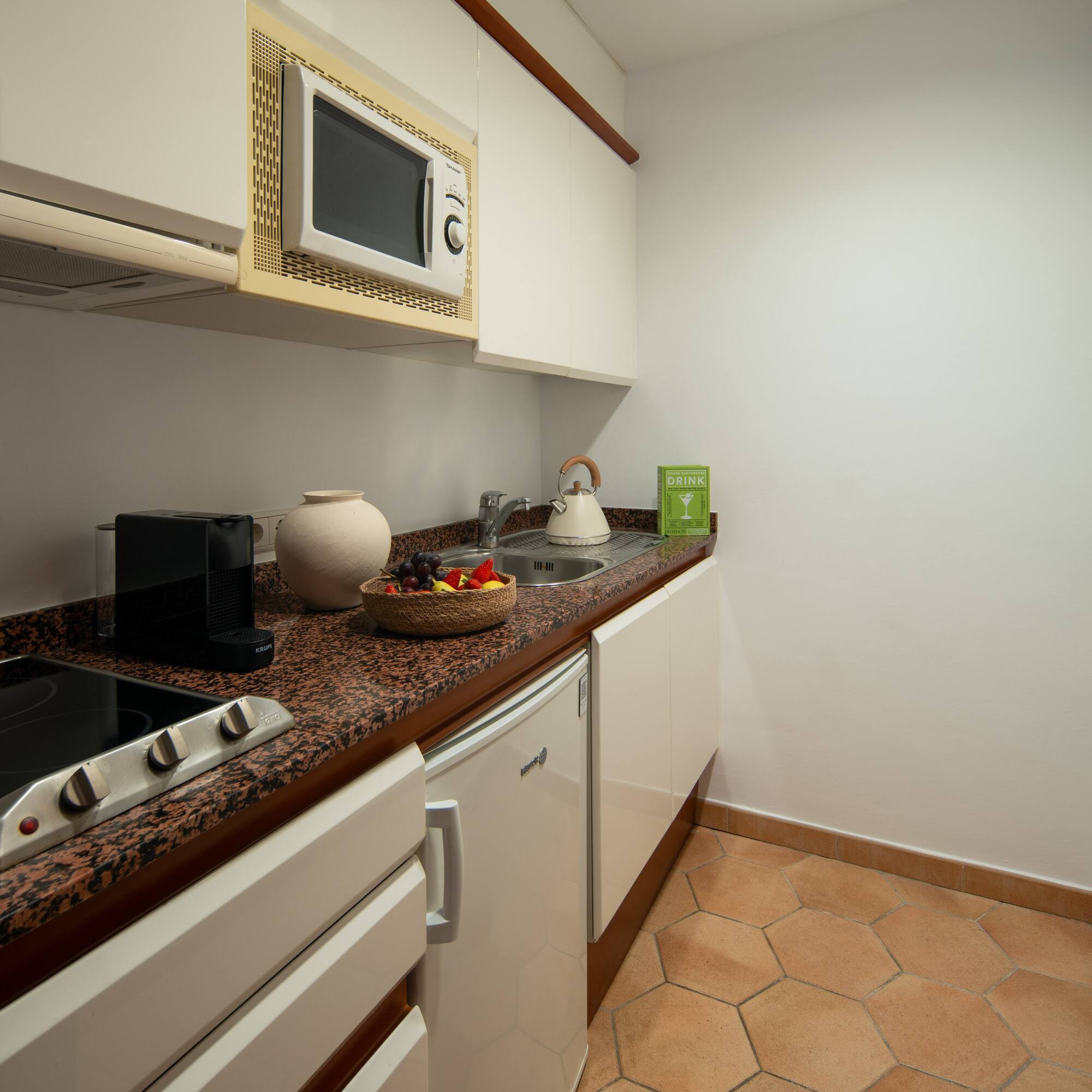 a kitchen with white cabinets and a bowl of fruit on a counter top