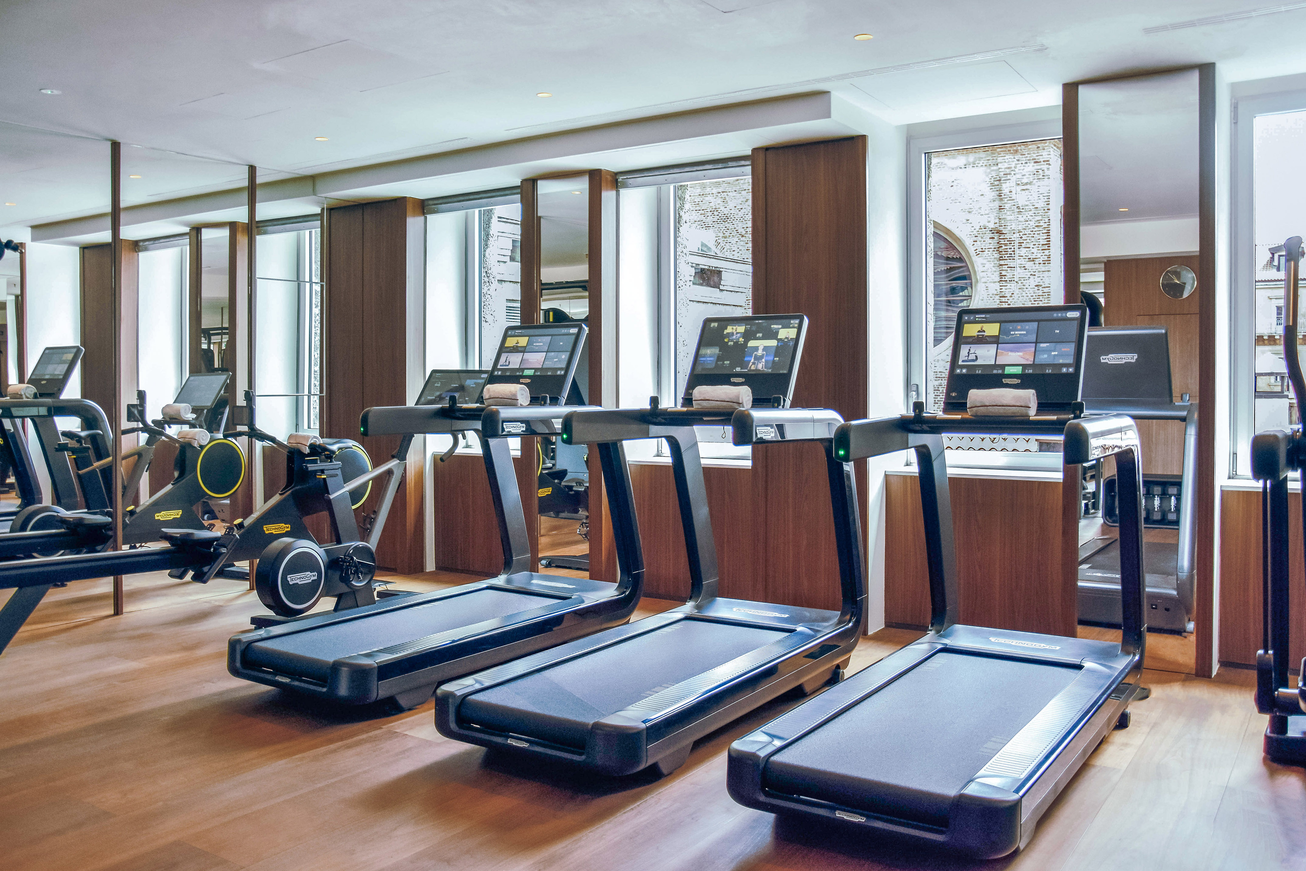 Bright, modern fitness center with Technogym treadmills and rowing machines.