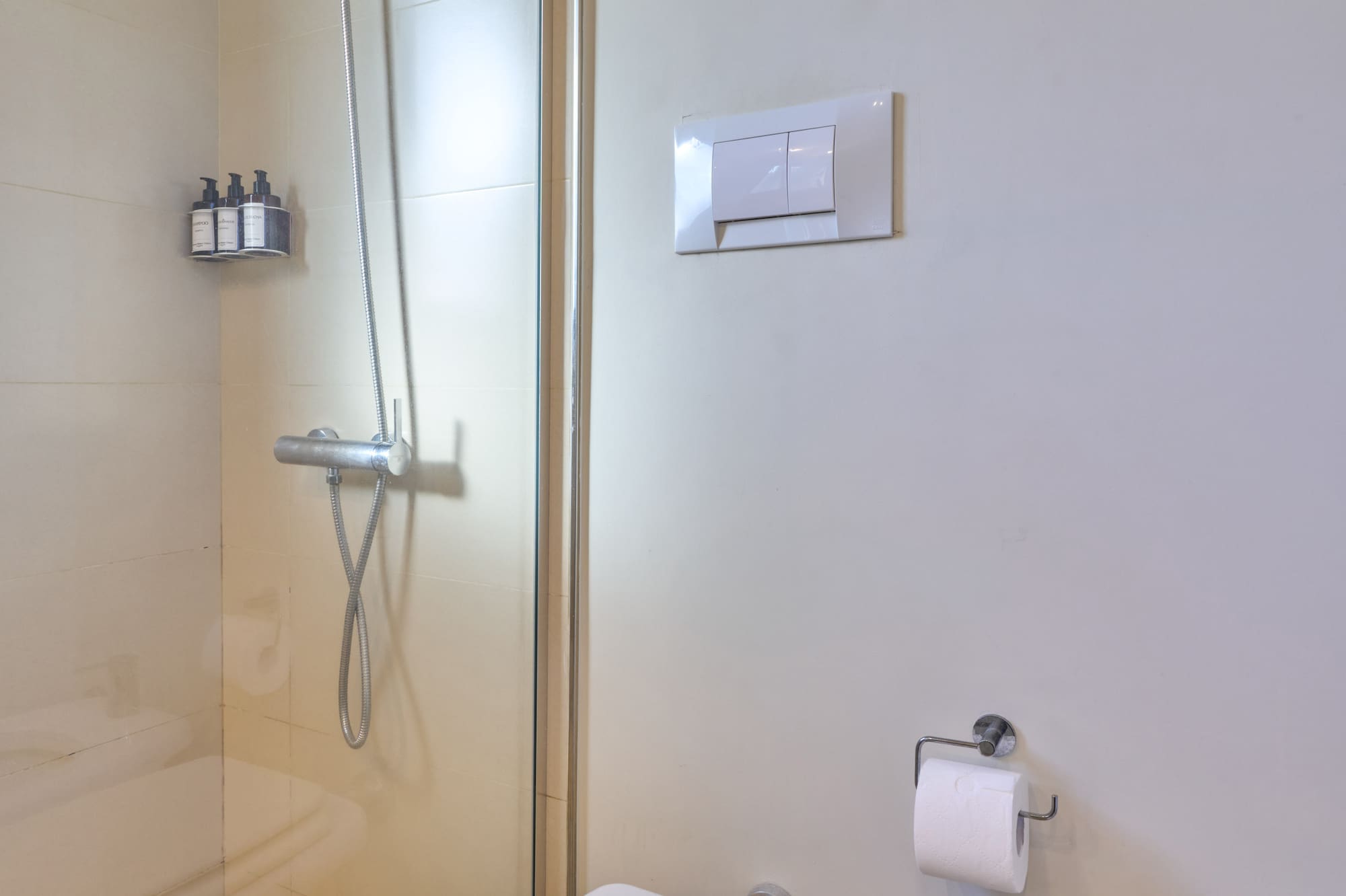 Clean bathroom interior with glass shower, toilet, and bidet.