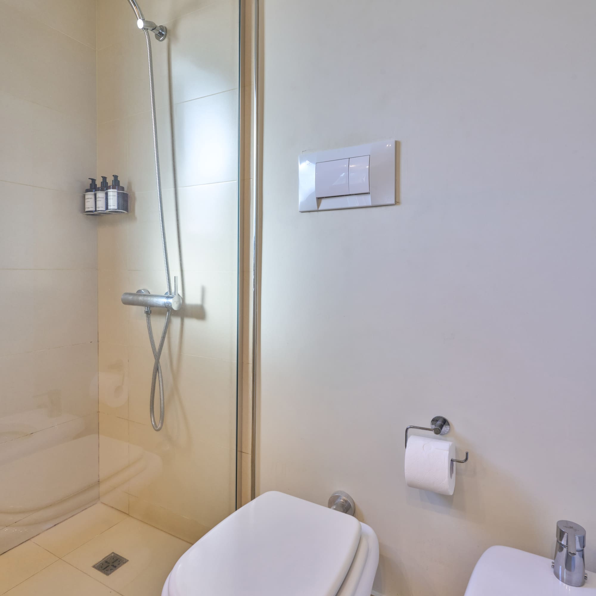 Clean bathroom interior with glass shower, toilet, and bidet.