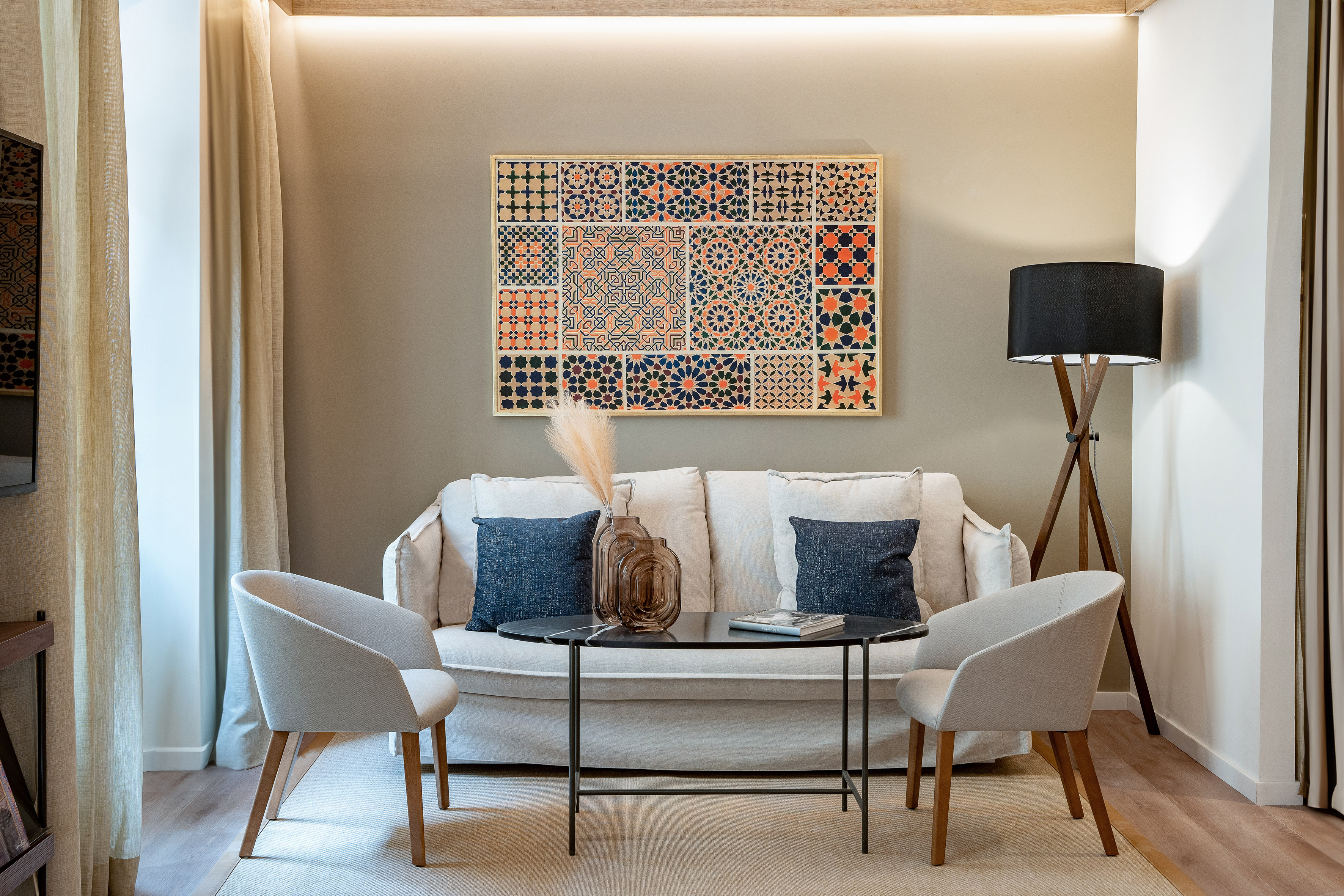 Living room with white sofa, Moroccan geometric art, coffee table, and armchairs.