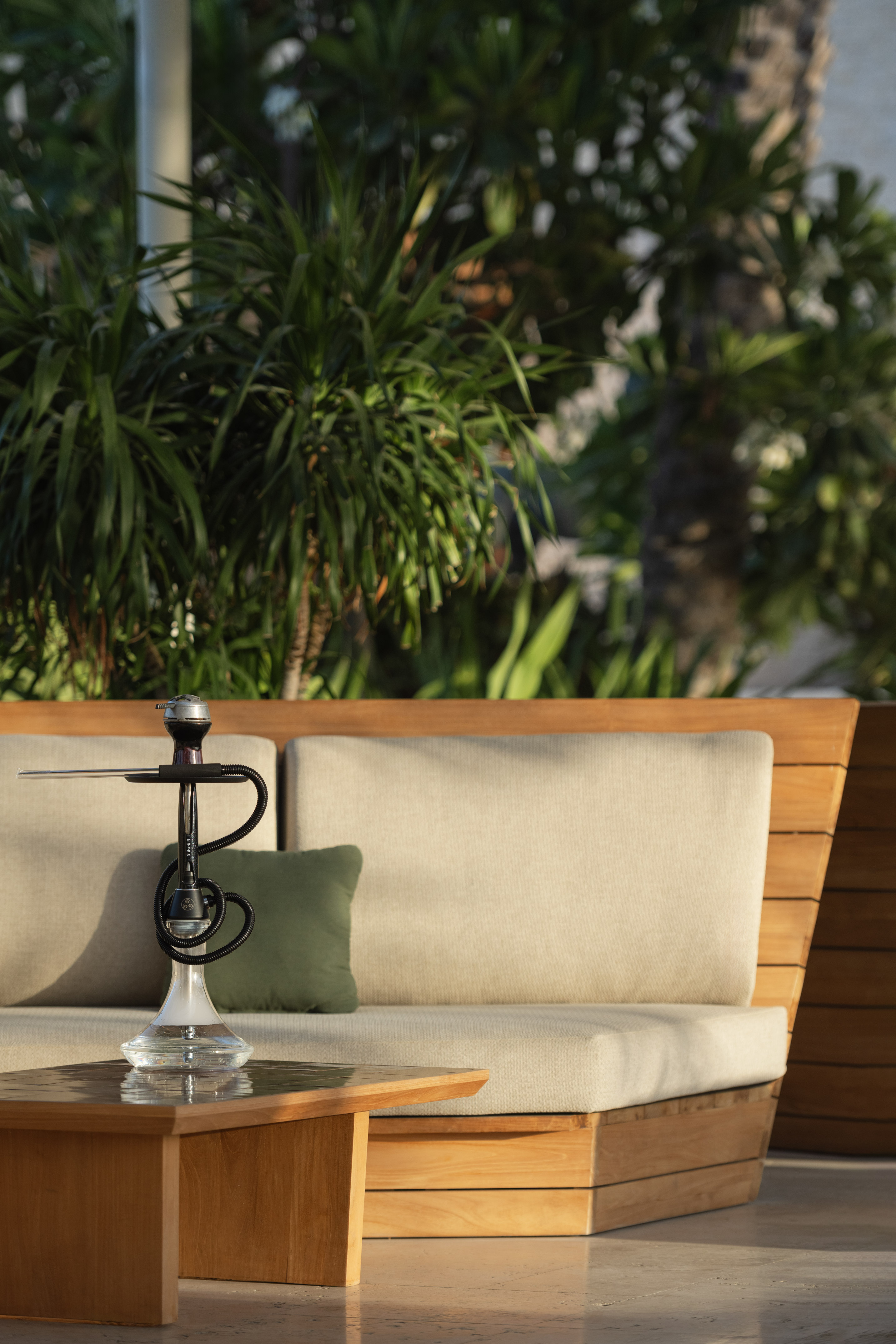 Outdoor lounge with modern wooden sofa, coffee table, and a sleek hookah.