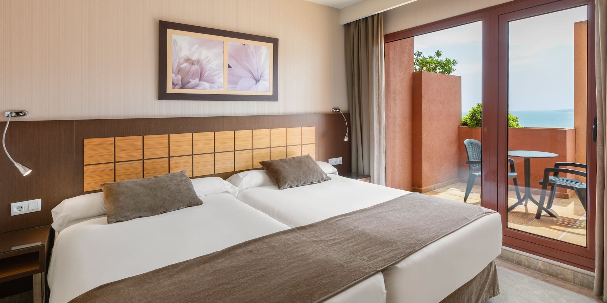 Hotel room with twin beds, private balcony, and sea view.
