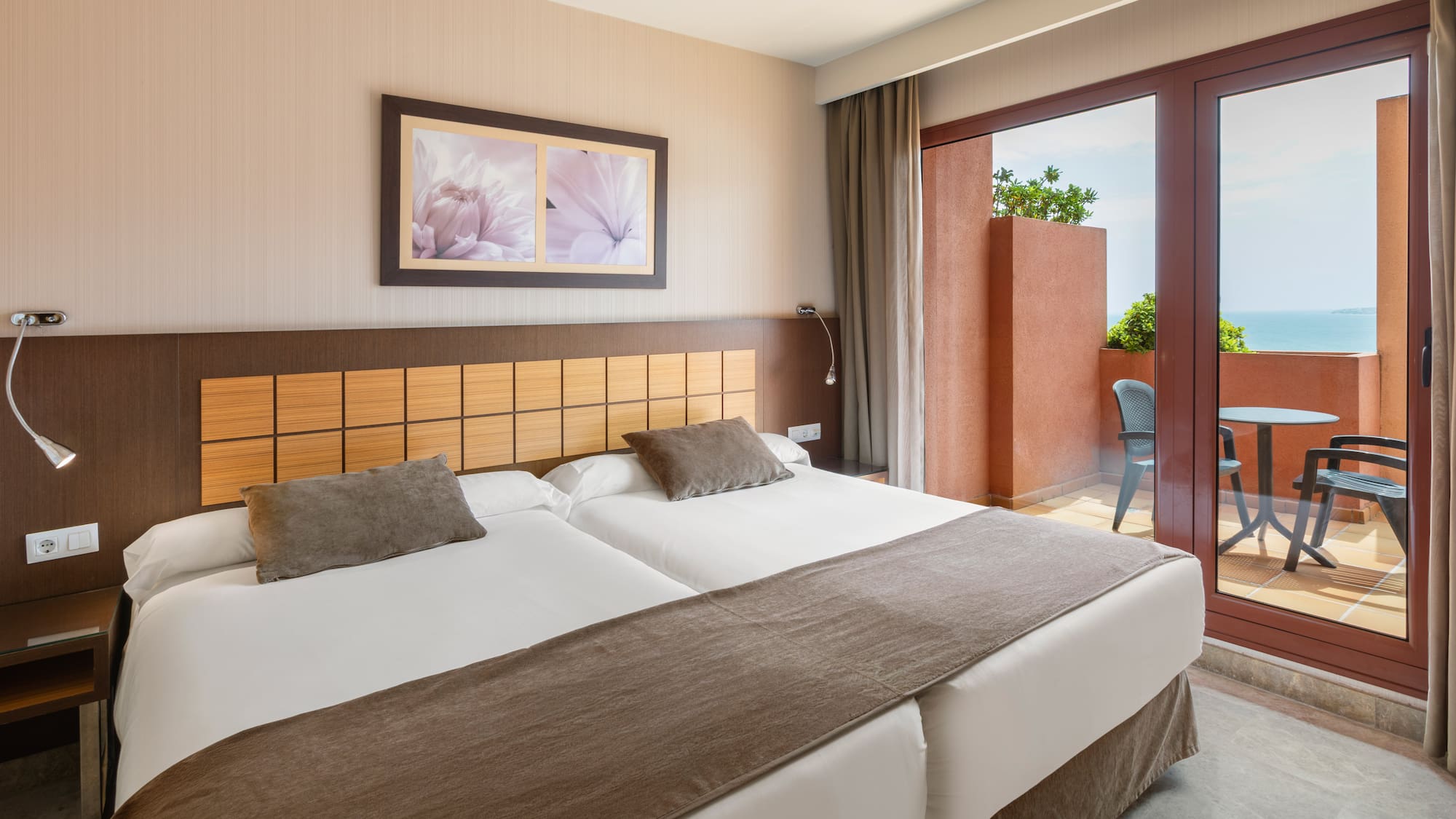Hotel room with twin beds, private balcony, and sea view.