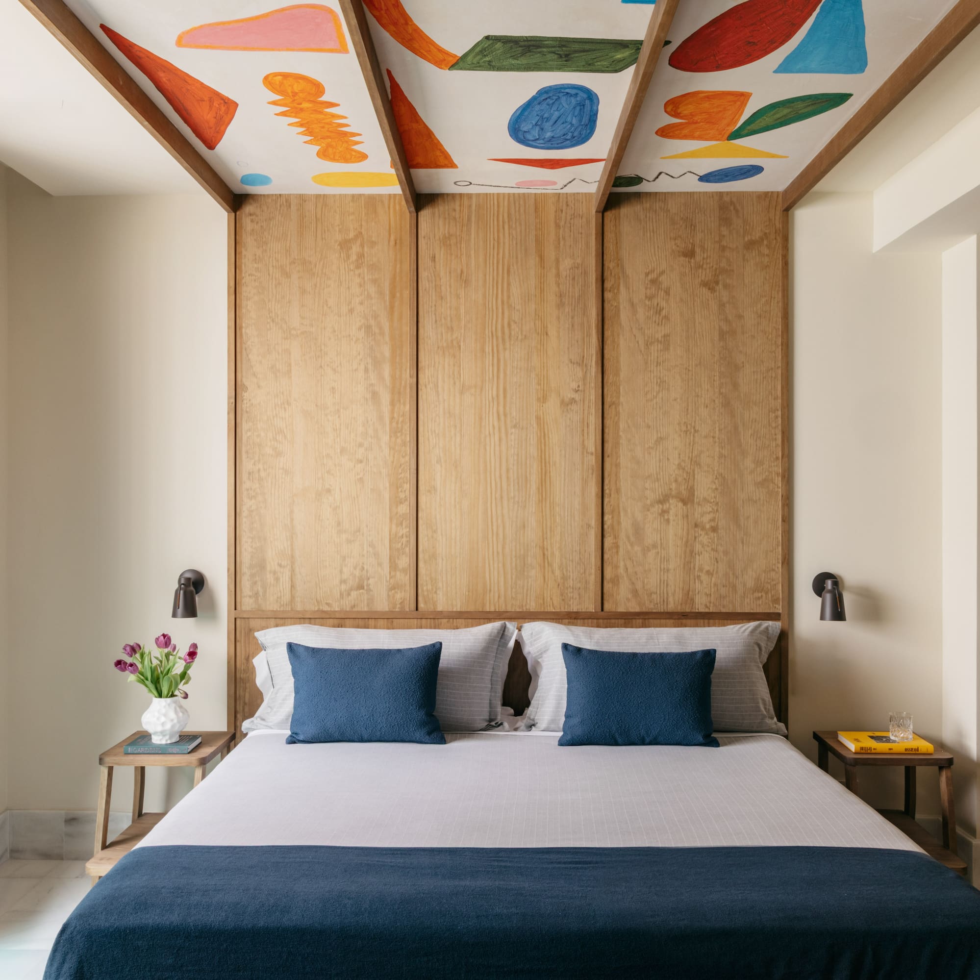 a bed with blue pillows and a wood paneled ceiling