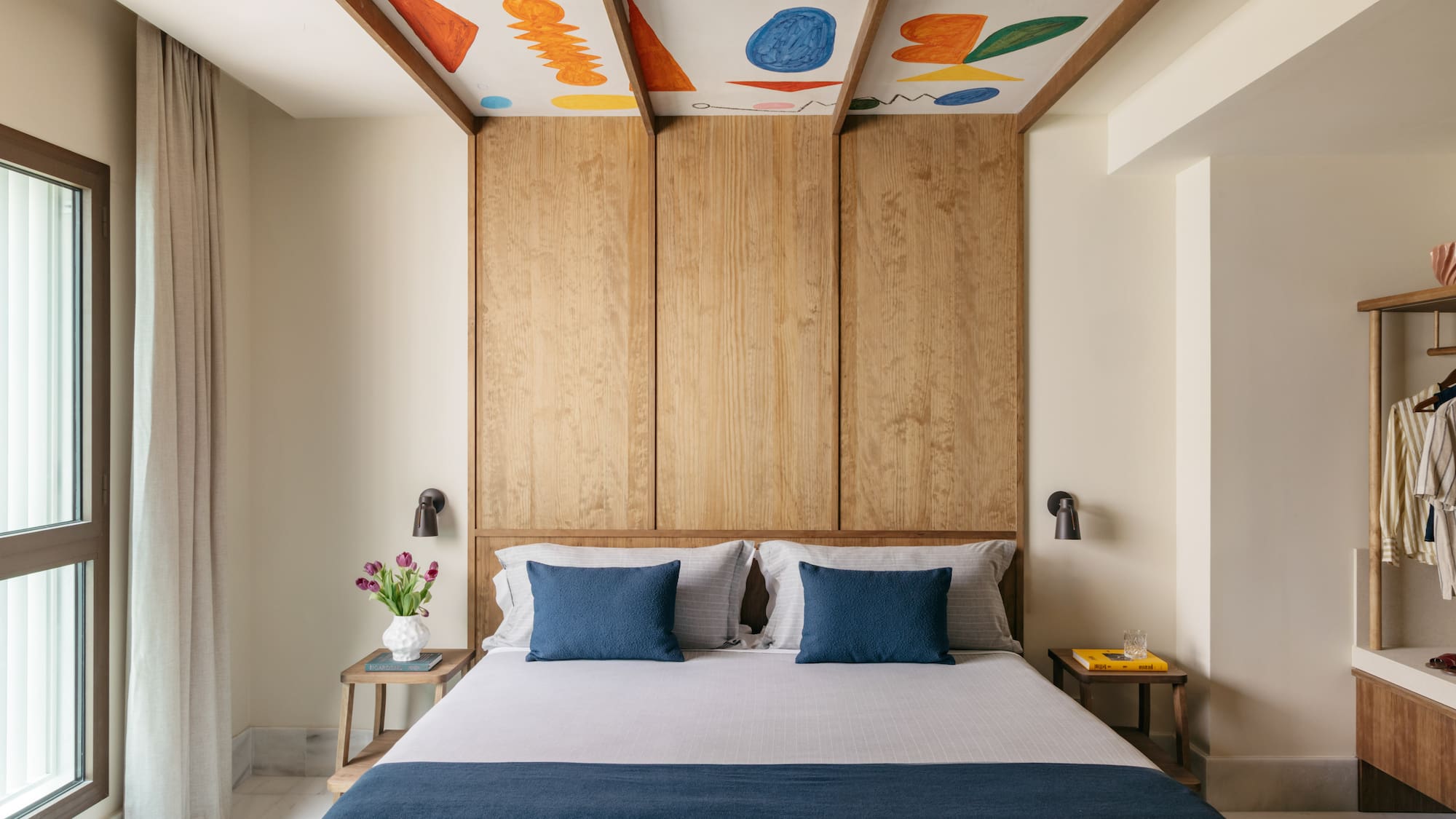 a bed with blue pillows and a wood paneled ceiling
